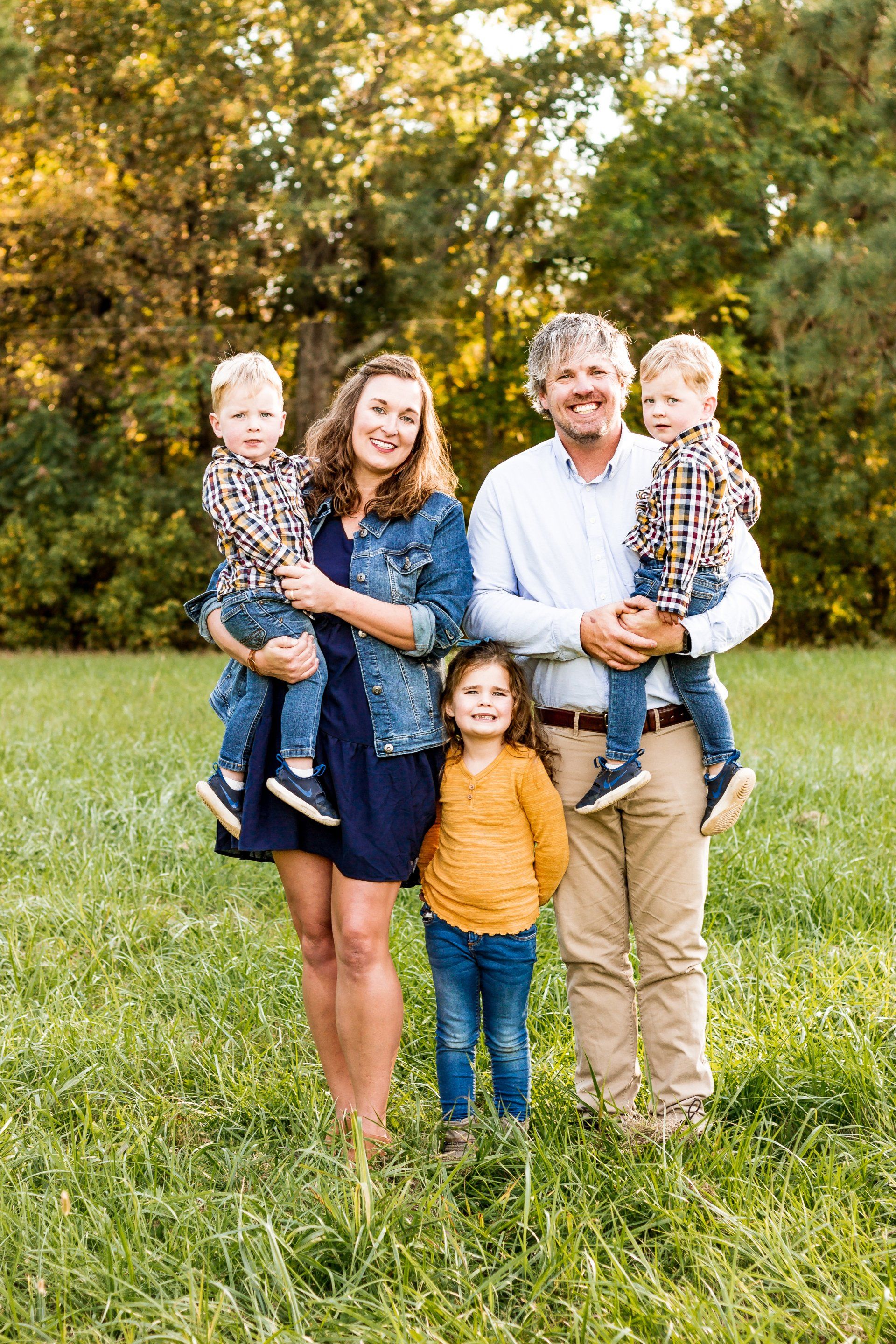 A family is posing for a picture in a grassy field.
