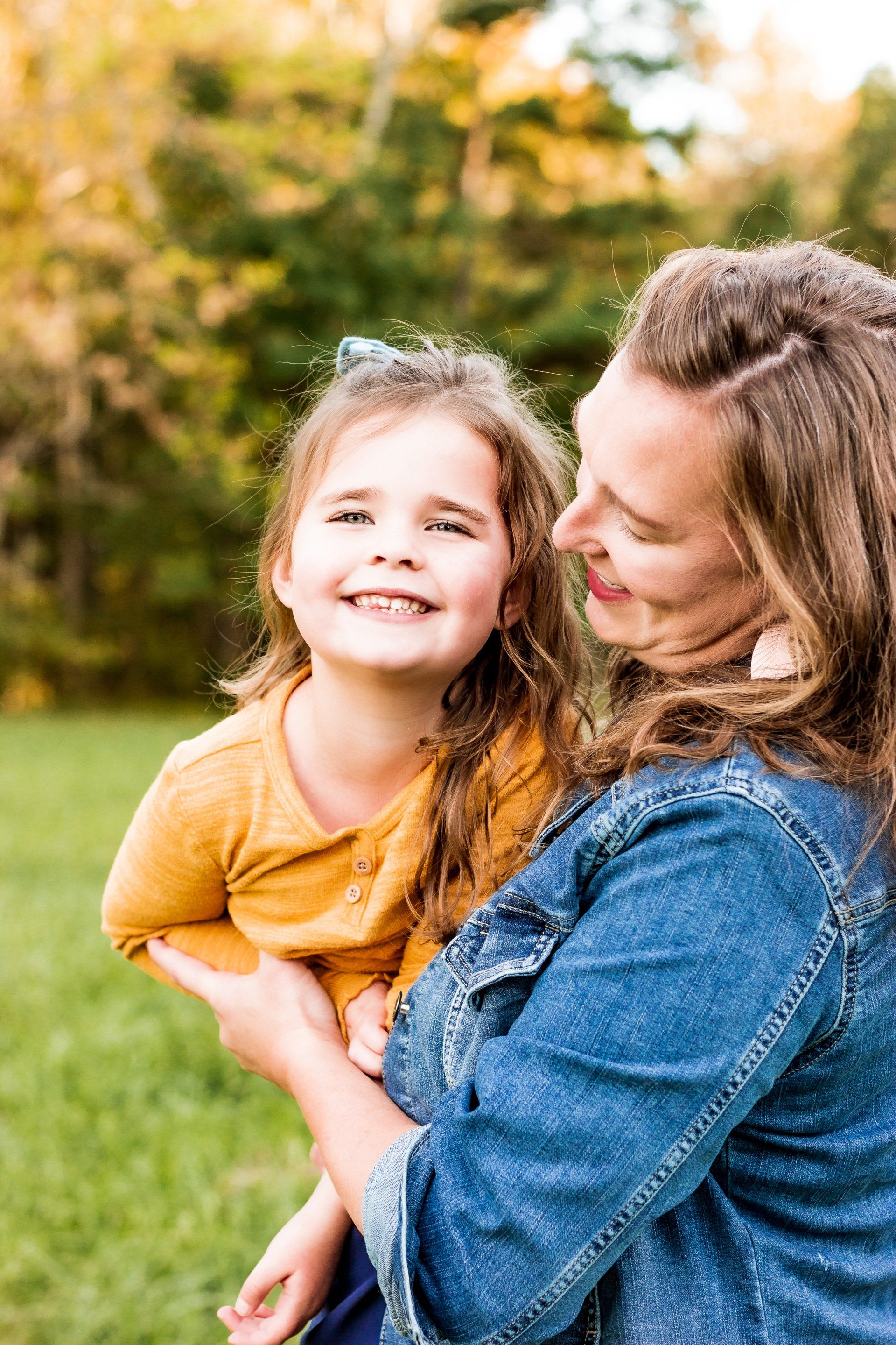 A woman is holding a little girl in her arms in a park.