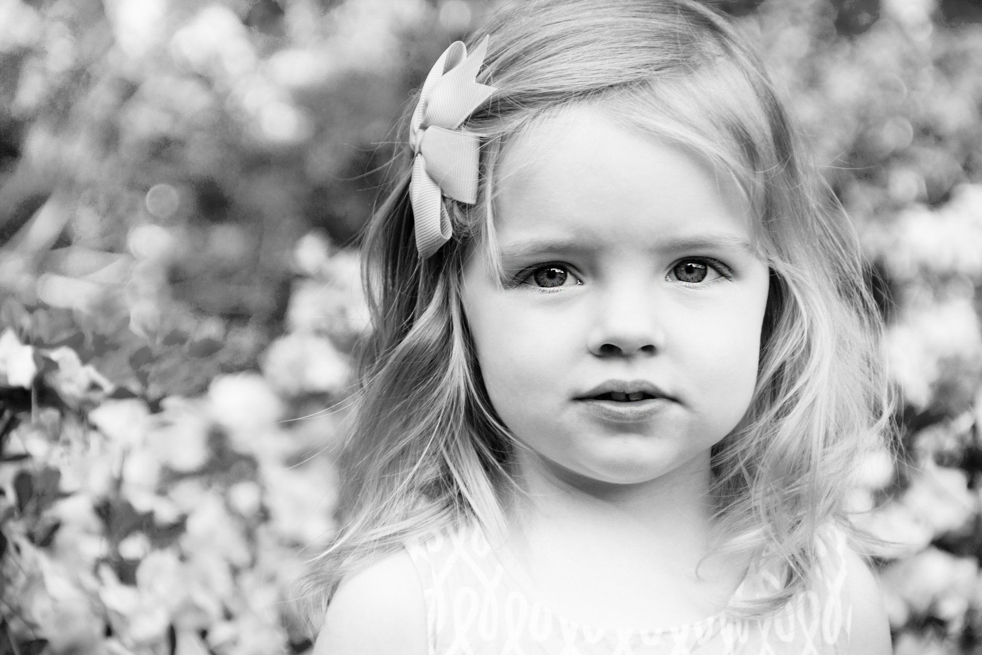 A black and white photo of a little girl with a flower in her hair.