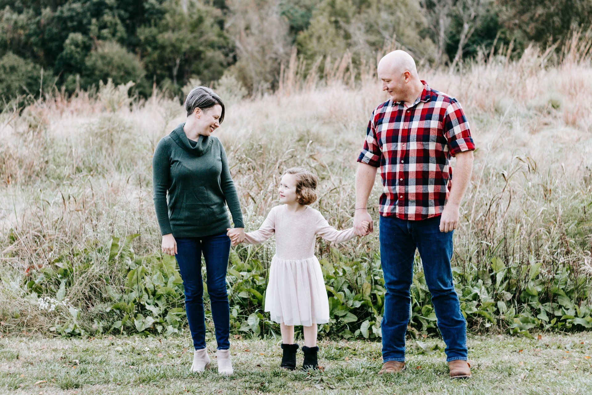 A family is standing in a field holding hands.