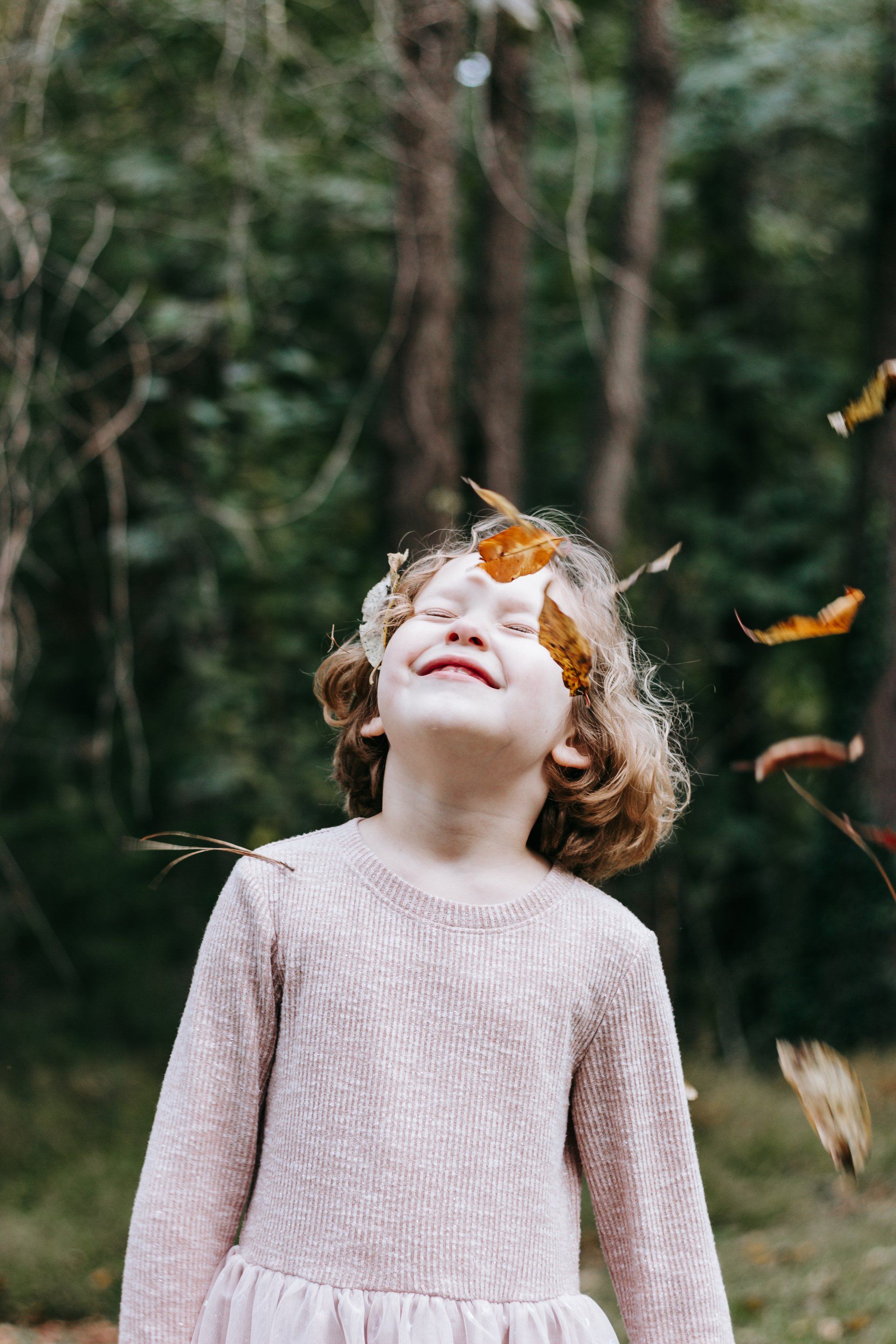A little girl is throwing leaves in the air.