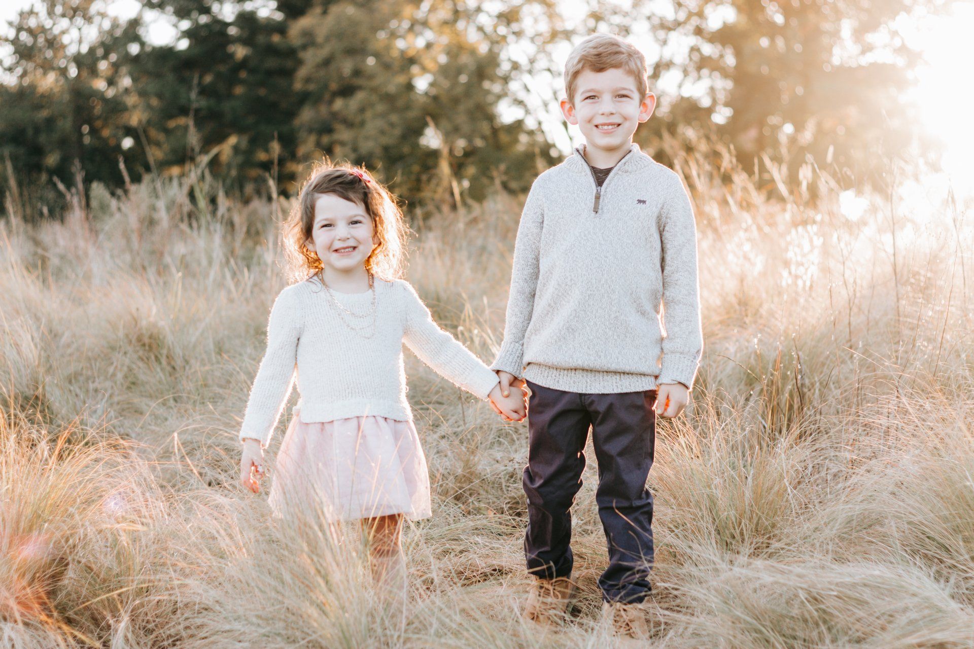 A boy and a girl are holding hands in a field.