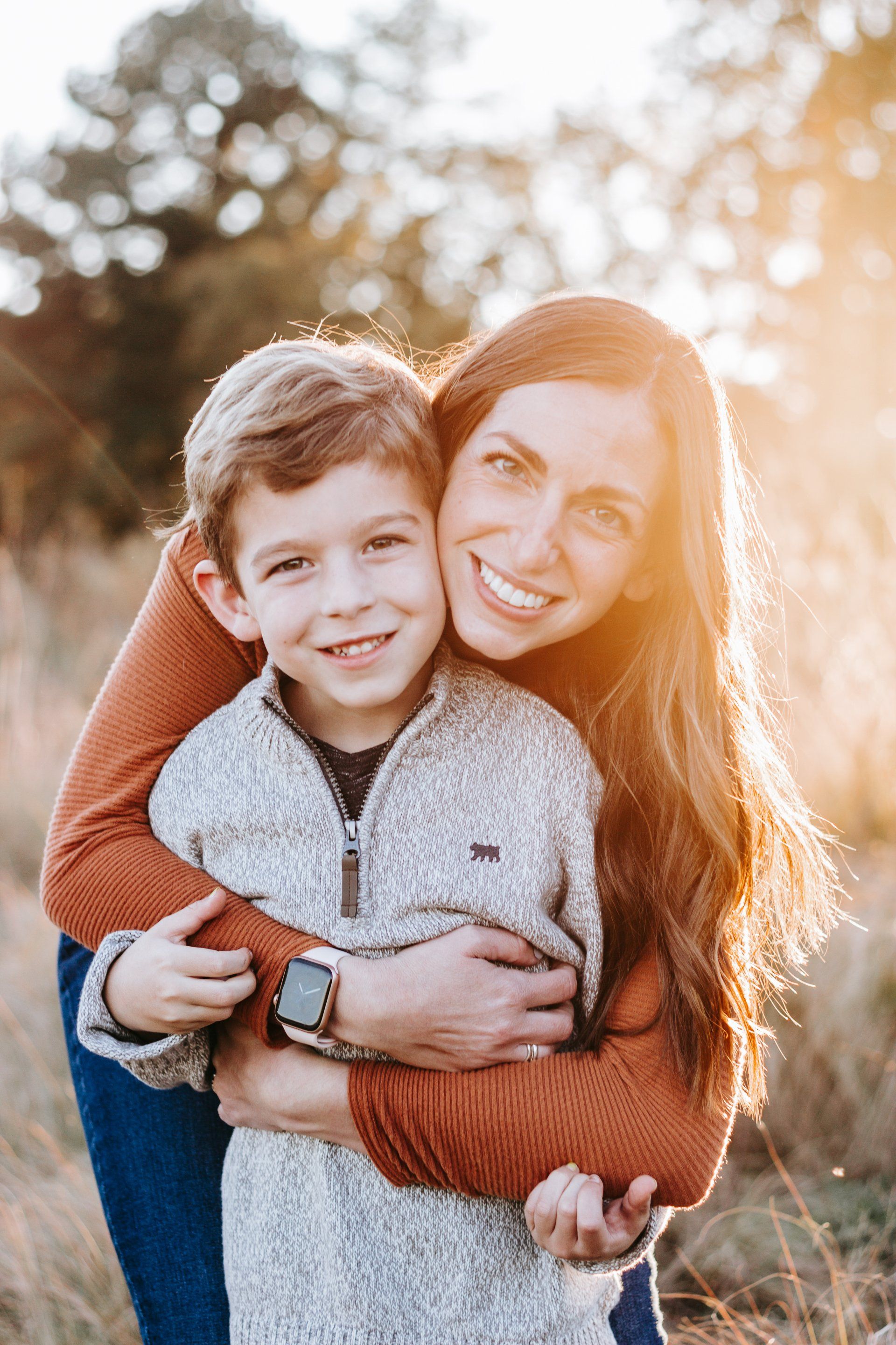 A woman is carrying a young boy on her back in a field.