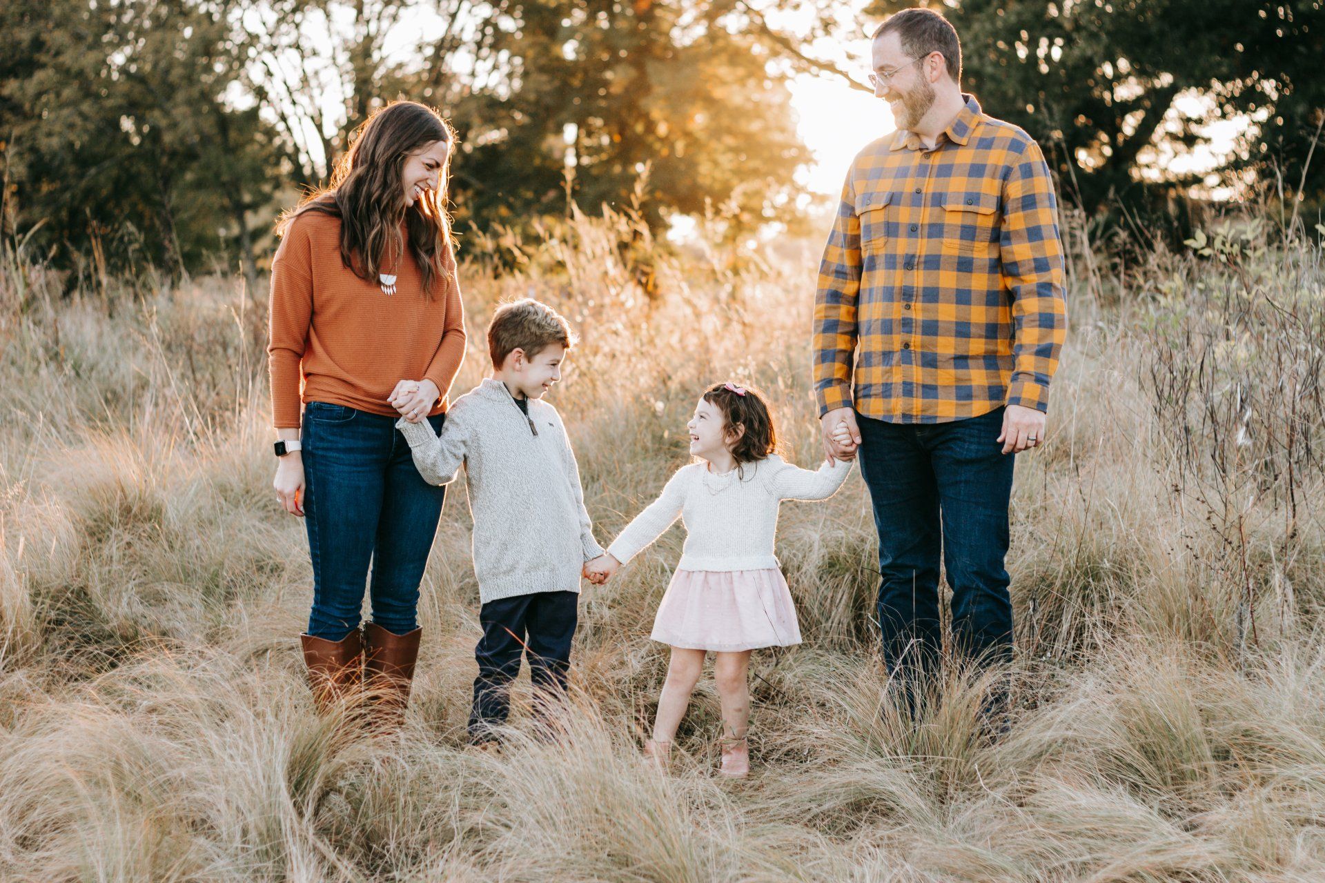 A family is standing in a field holding hands.