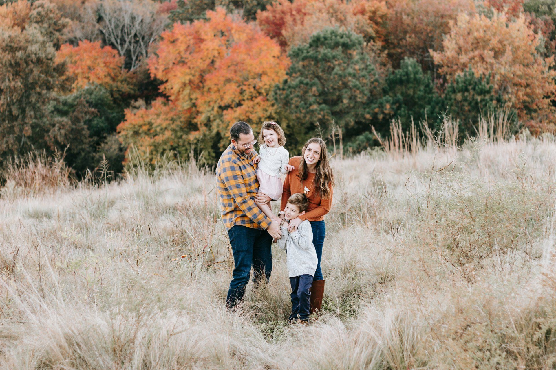 A family is standing in a field holding hands.