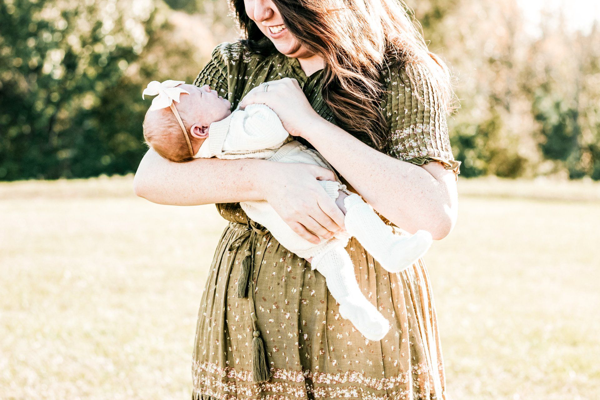 A woman is holding a baby in her arms in a field.