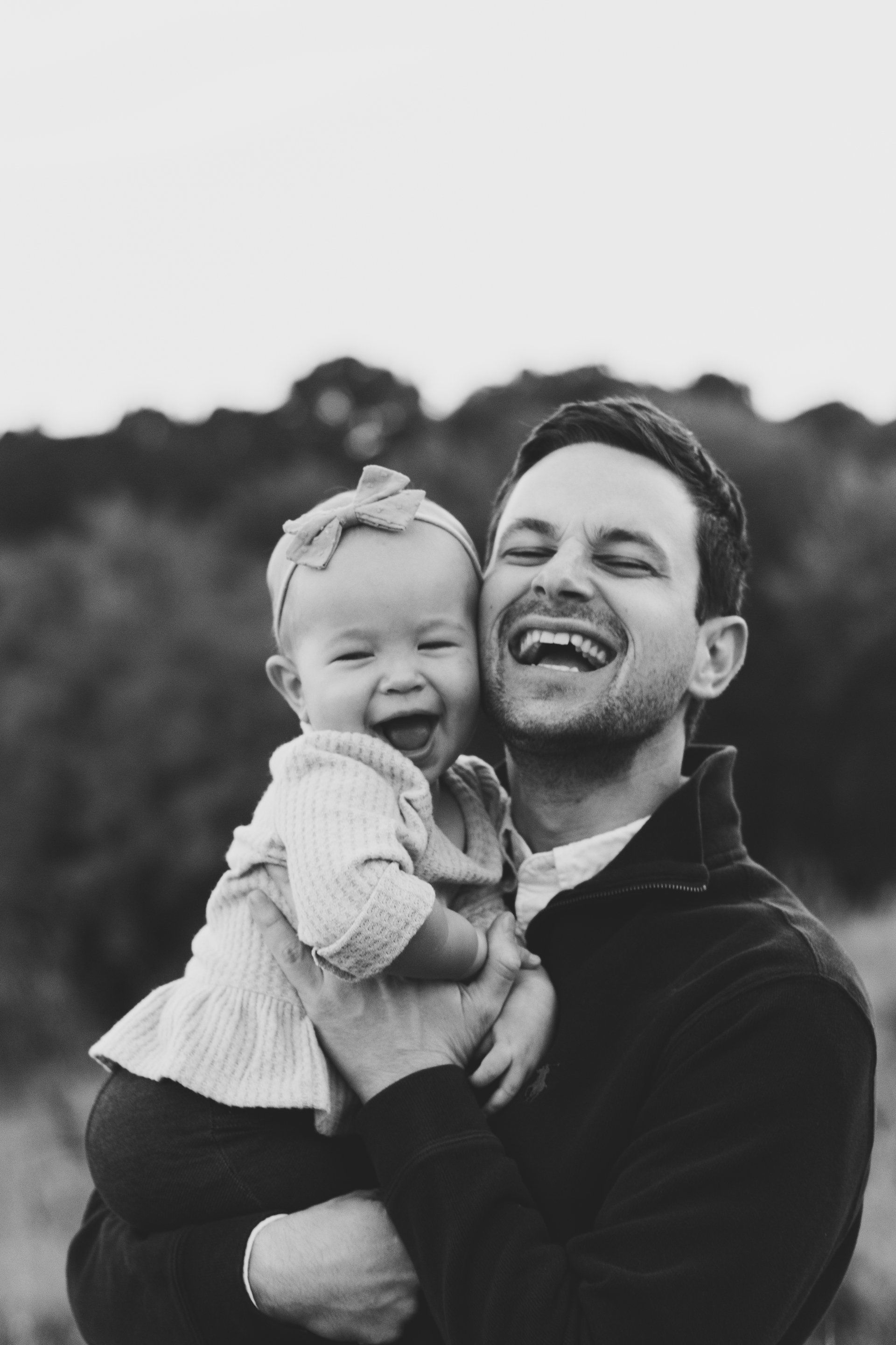 A man is holding a baby girl in his arms and the baby is laughing.