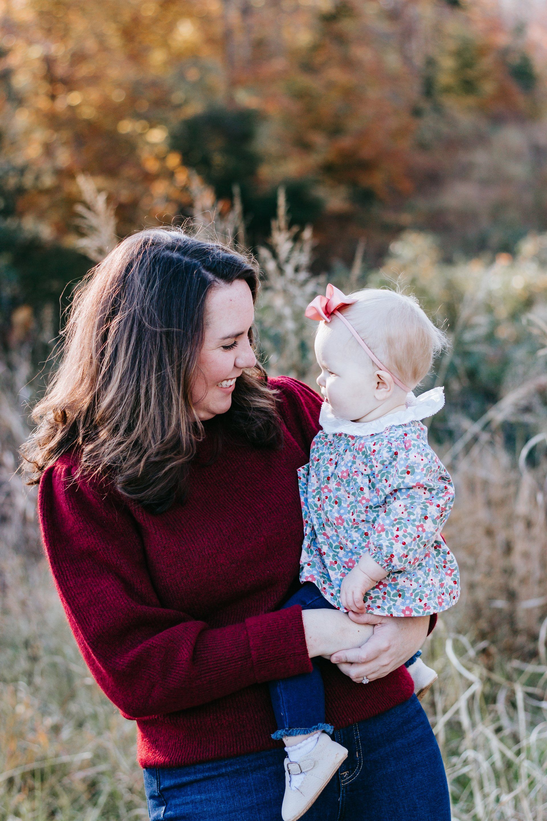 A woman is holding a baby in her arms in a field.