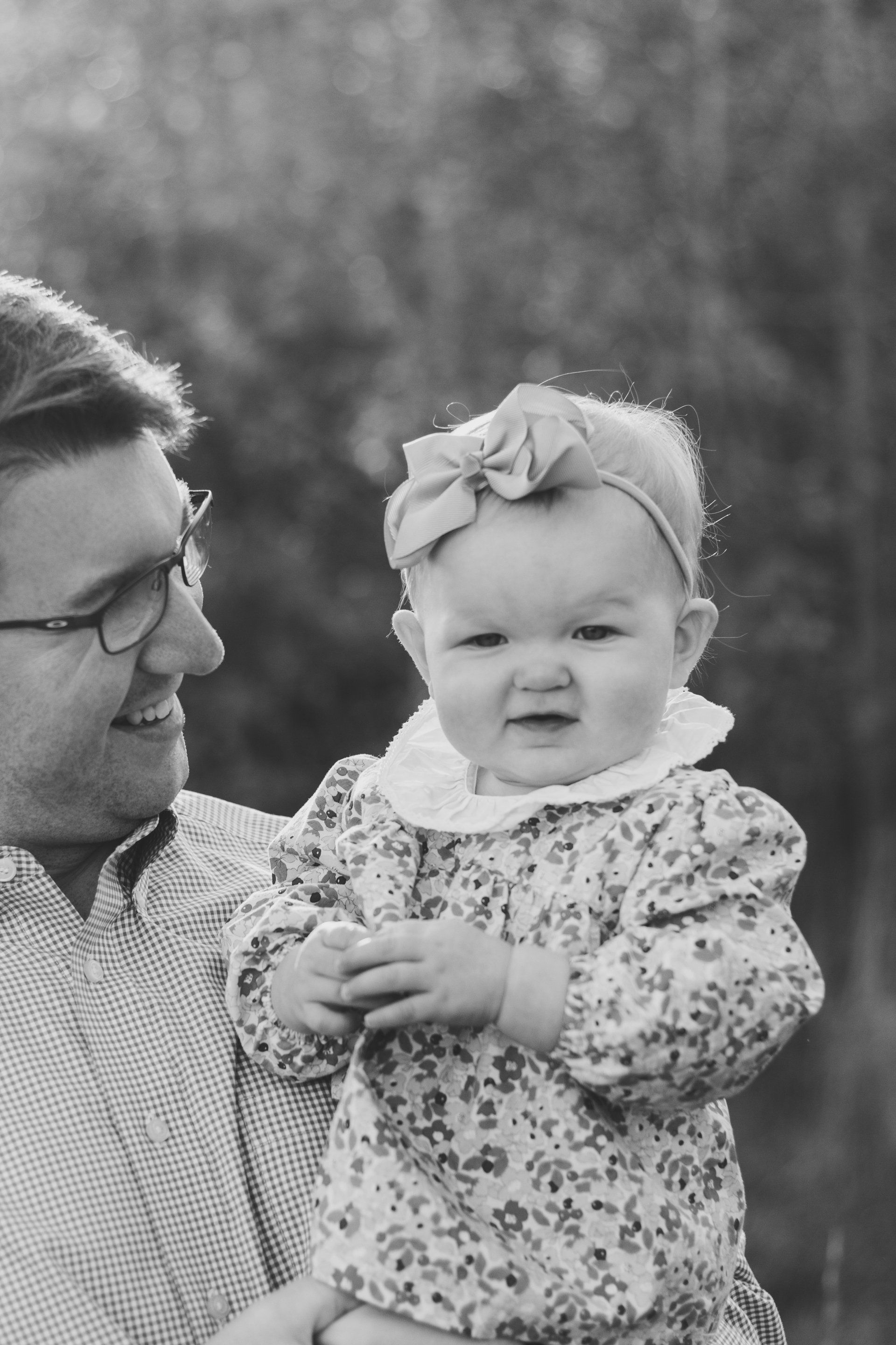 A man is holding a baby girl in his arms in a black and white photo.