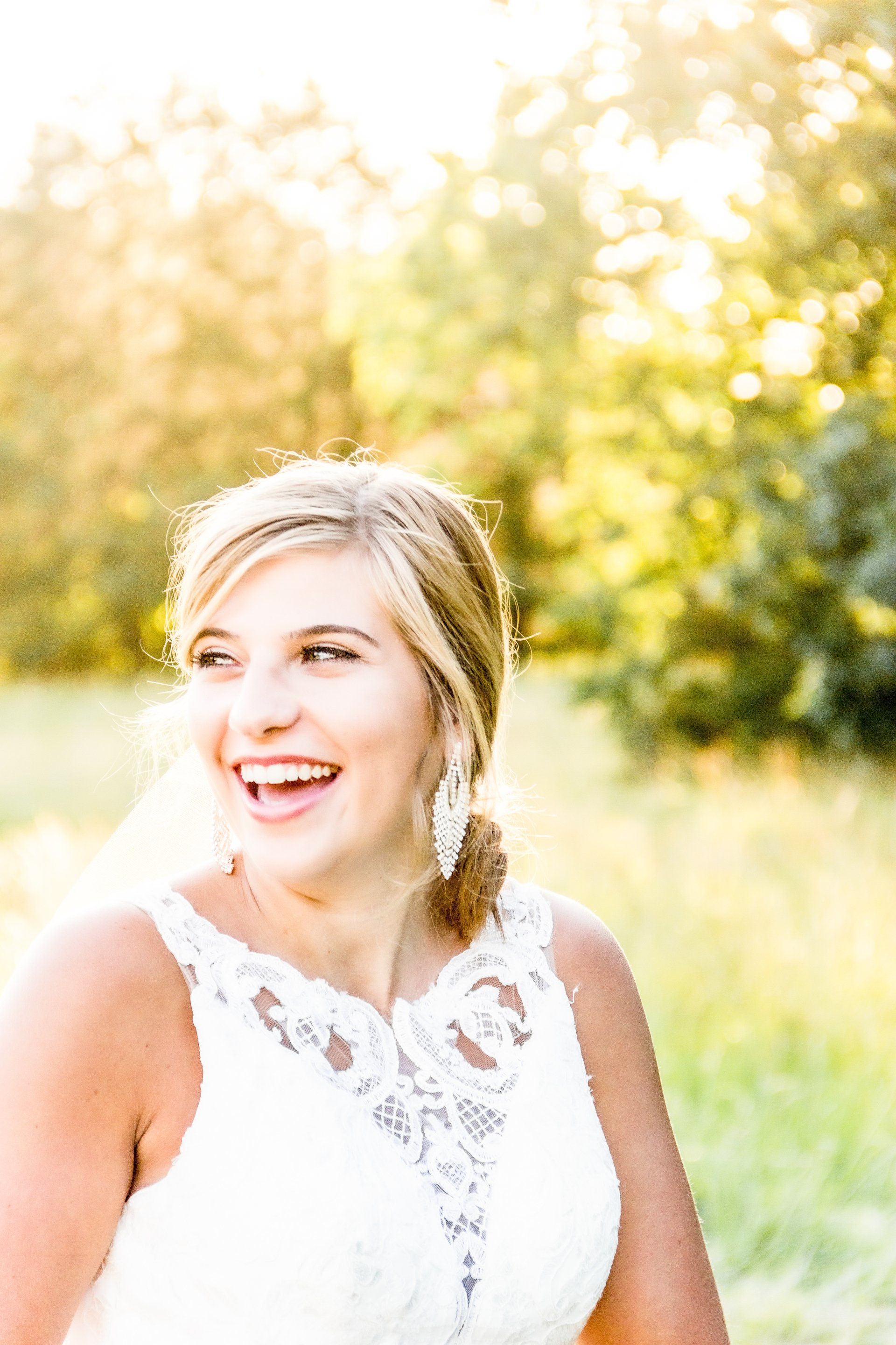 A woman in a white dress is laughing in a field.