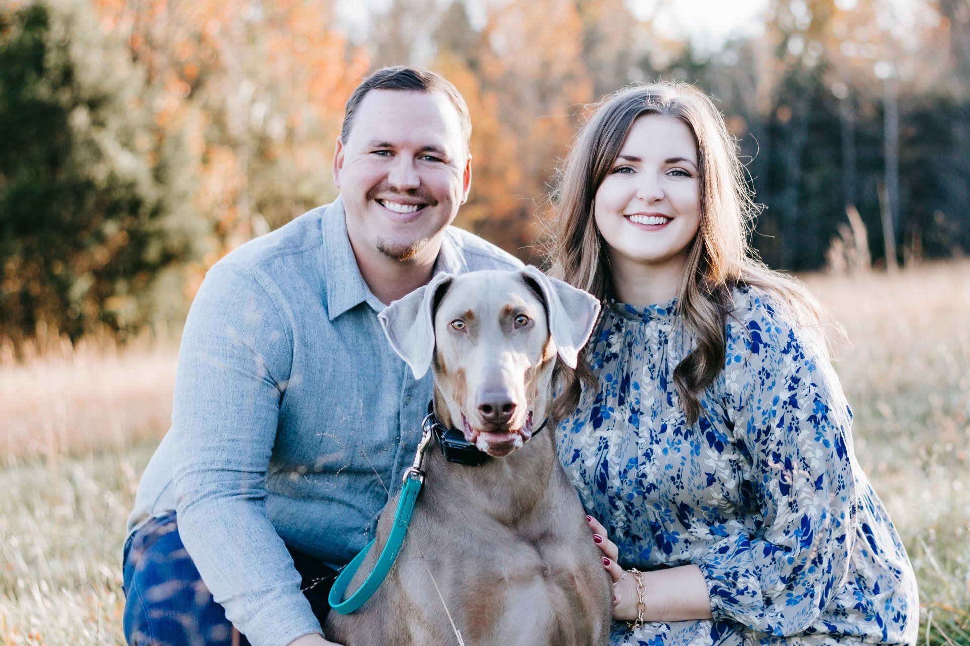 A man and a woman are posing for a picture with their dog.