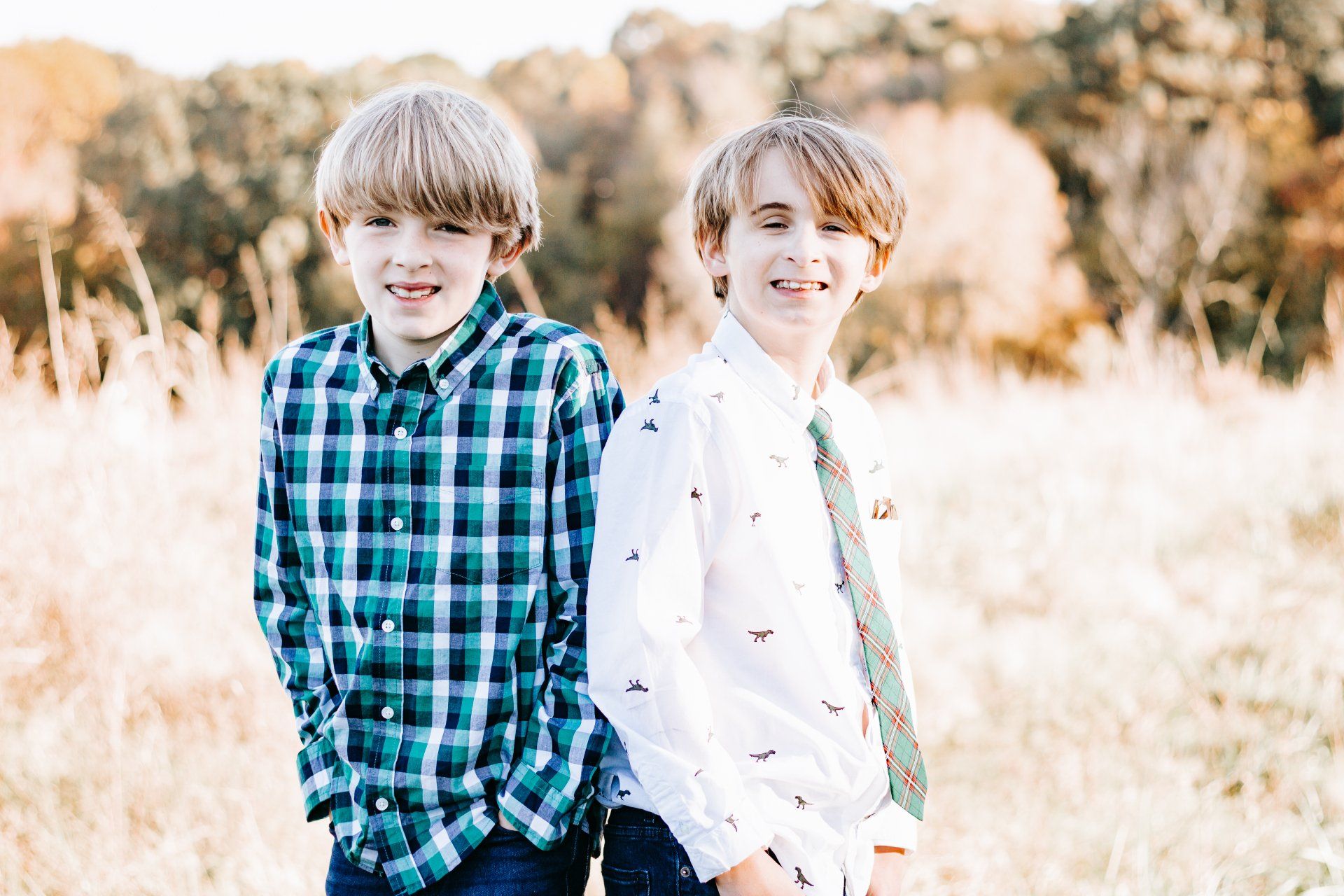 Two young boys are standing next to each other in a field.
