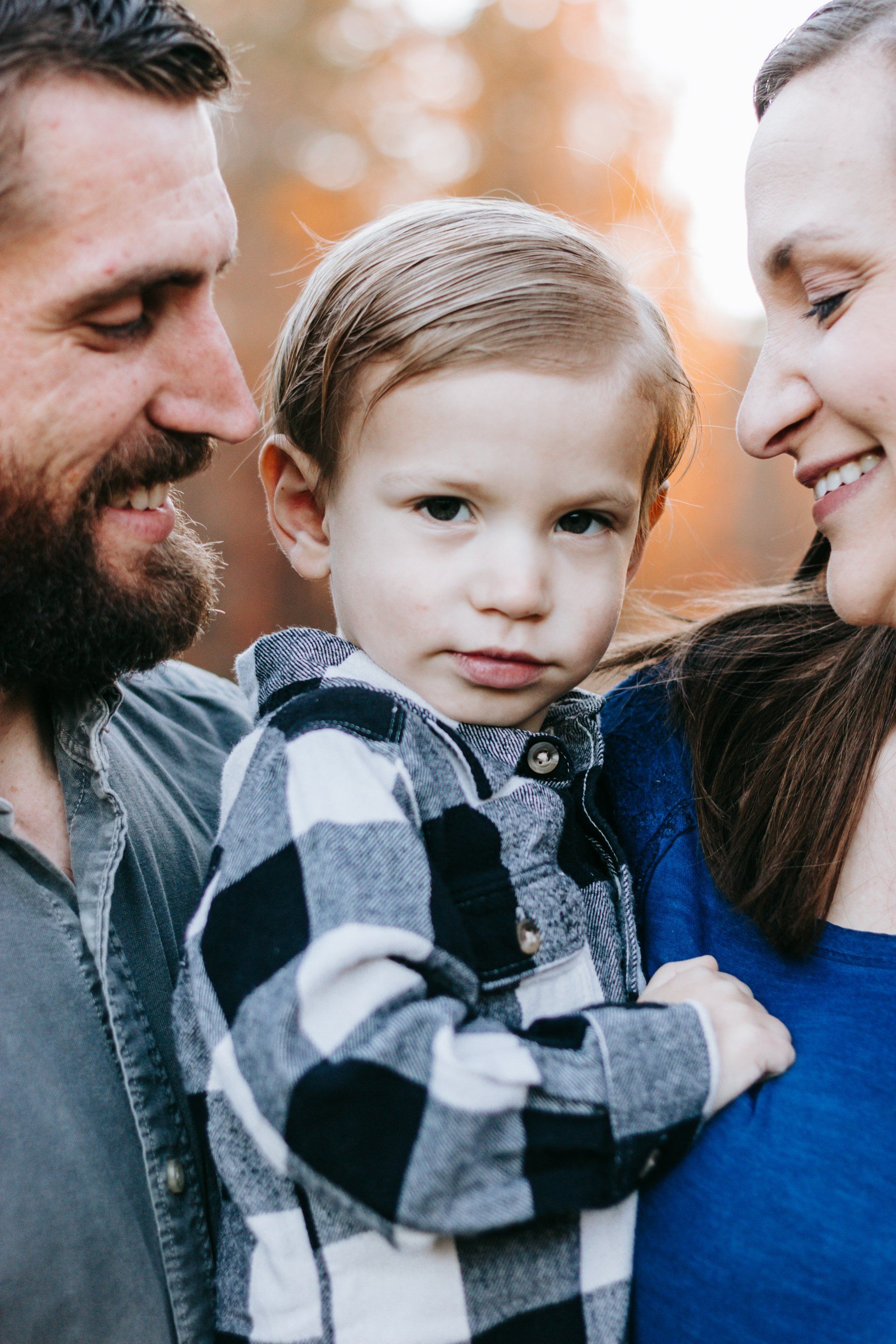 A man and woman are holding a little boy in their arms.