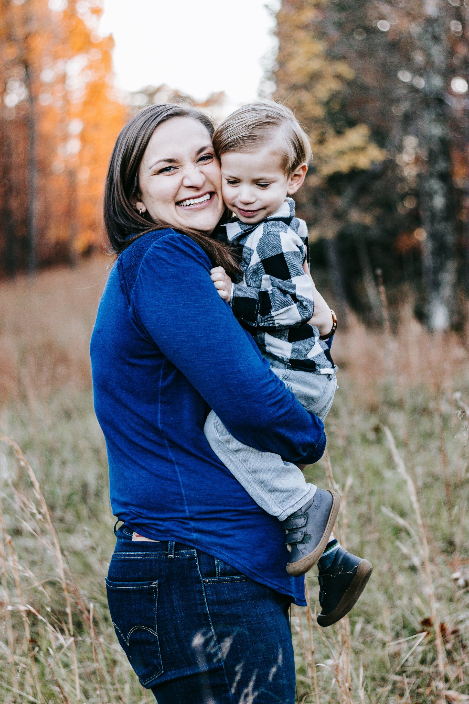 A woman is holding a baby in her arms in a field.