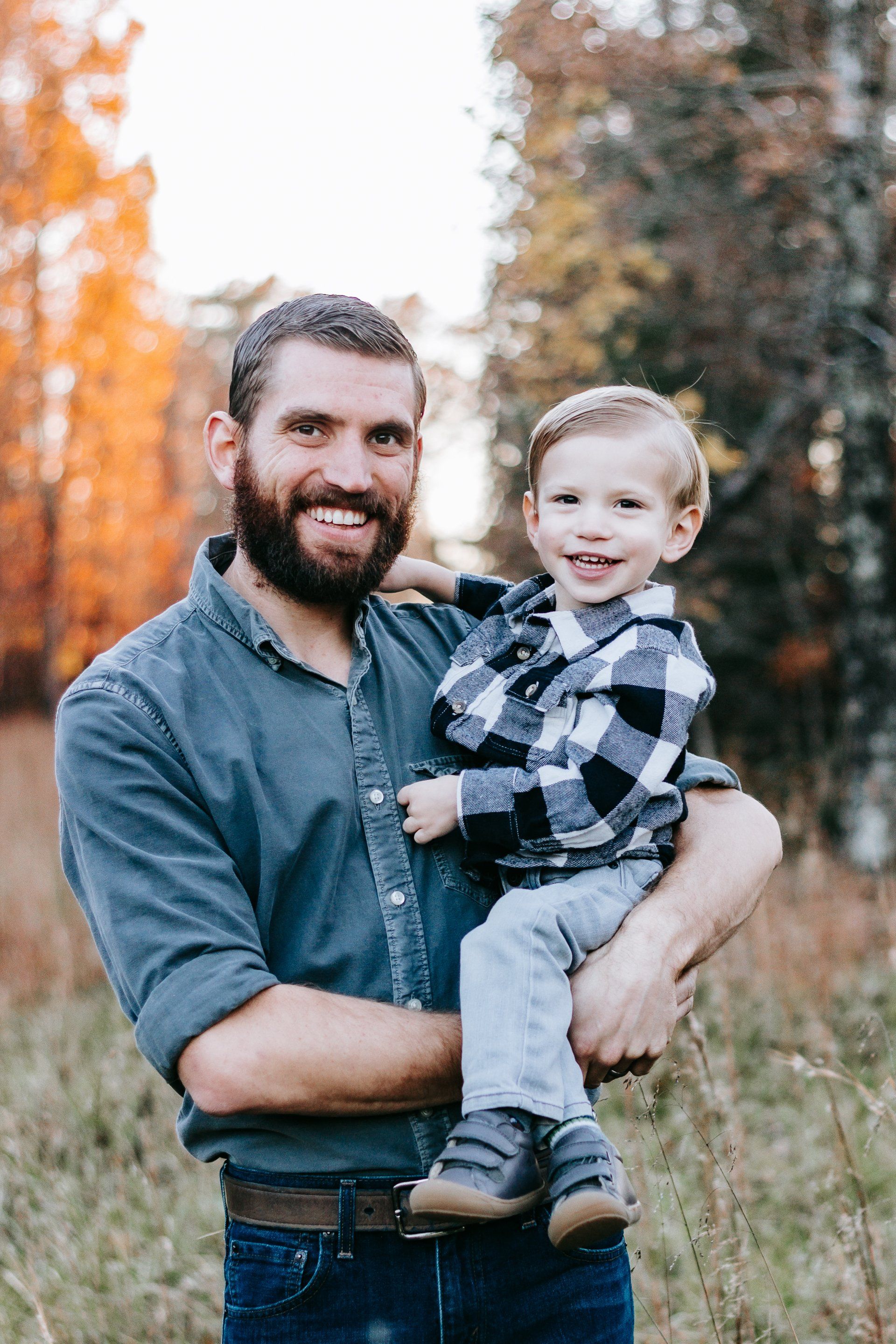 A man is holding a little boy in his arms in a field.