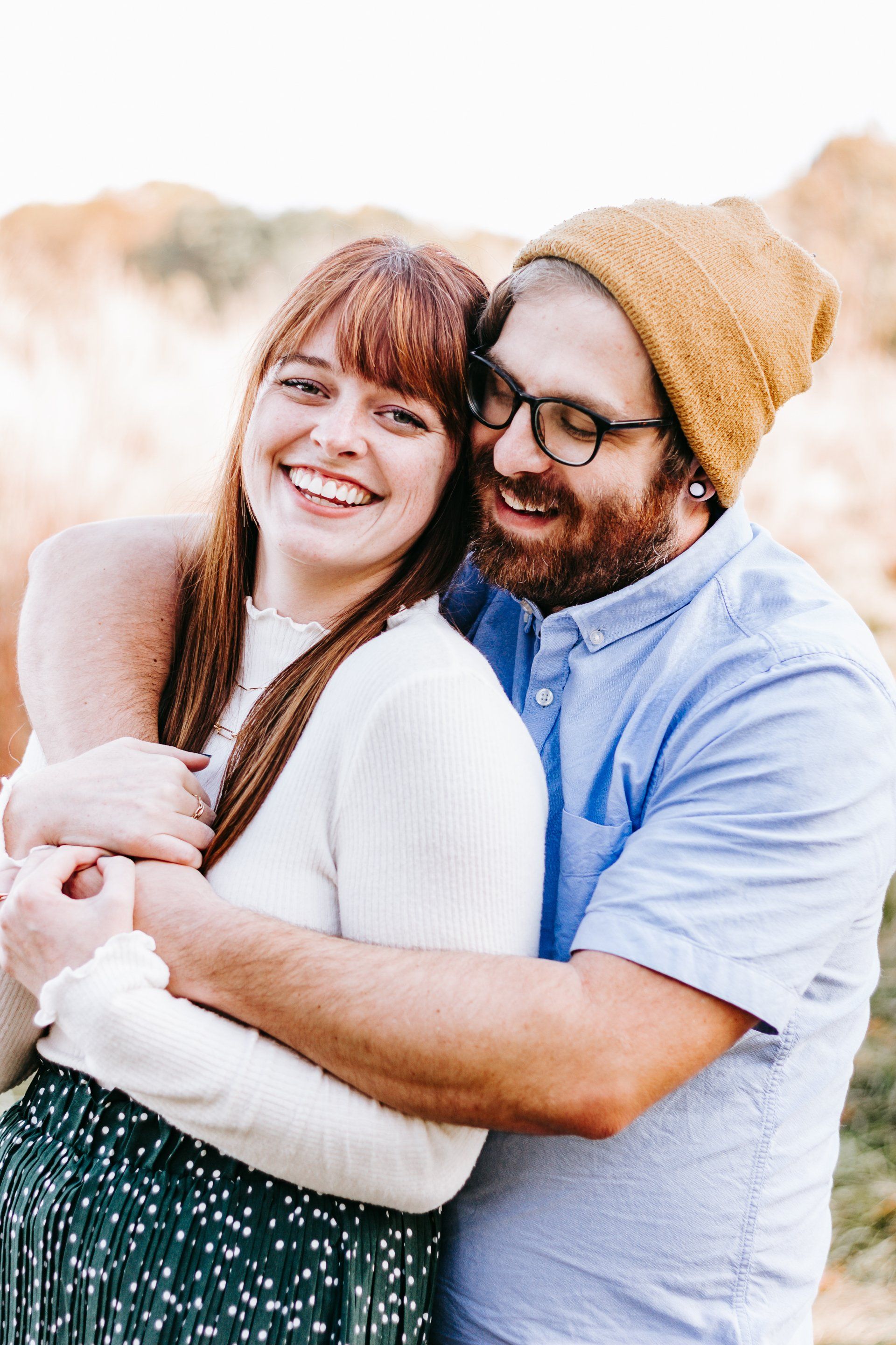 A man and a woman are hugging each other and smiling.