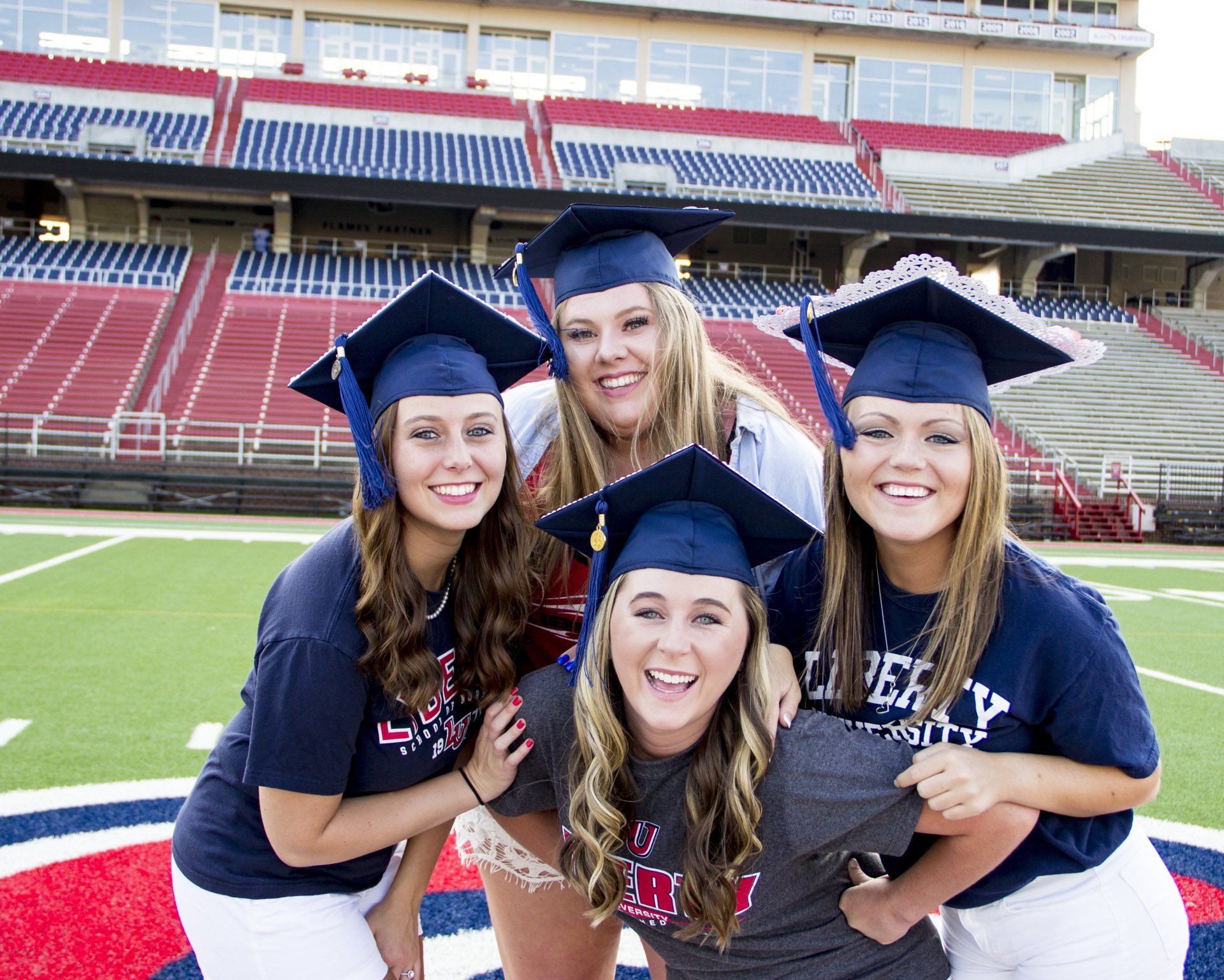 Four girls wearing graduation caps are posing for a picture
