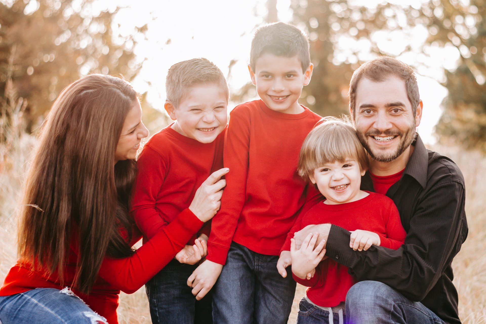 A family is posing for a picture together while wearing red sweaters.
