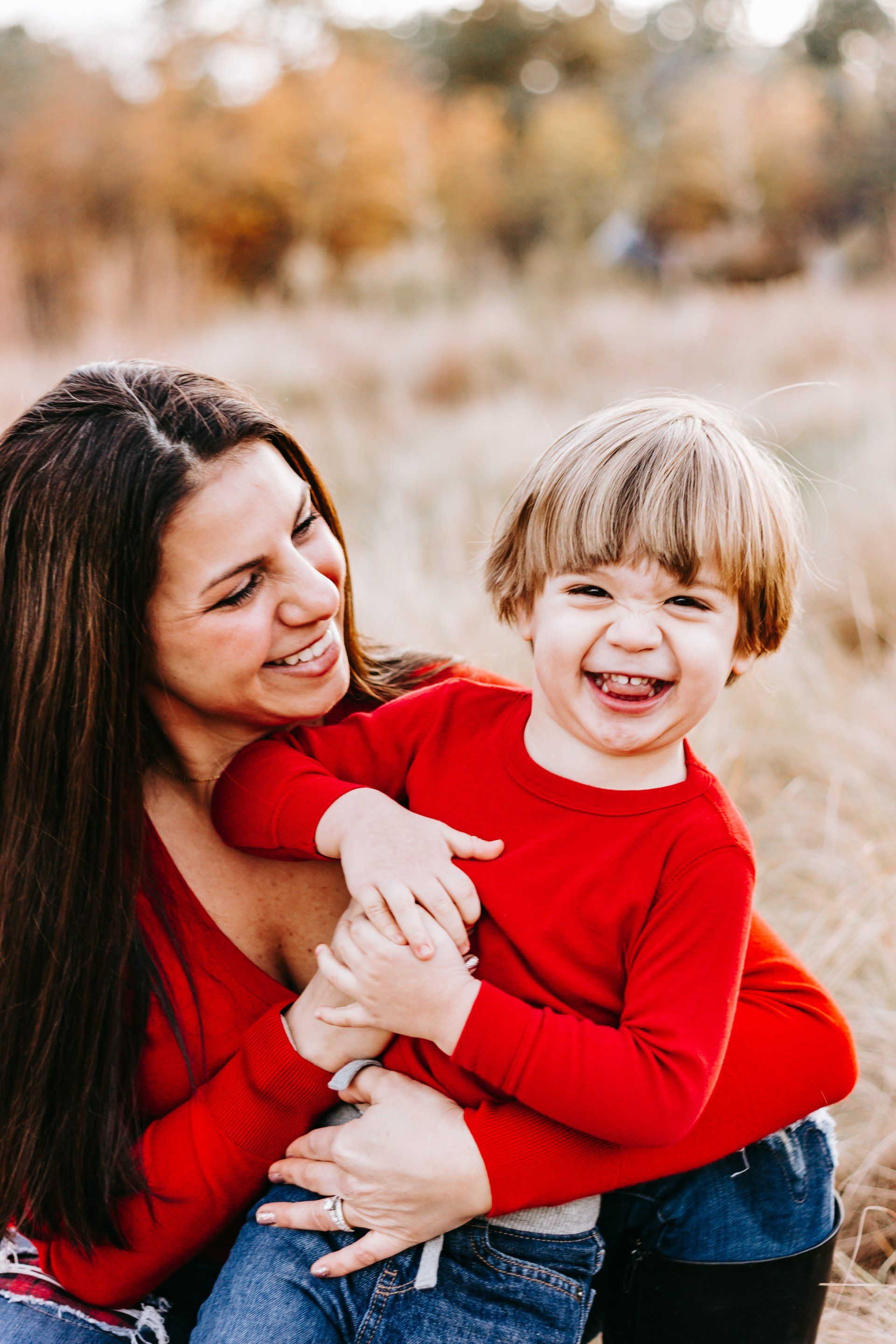 A woman is holding a little boy in her arms in a field.