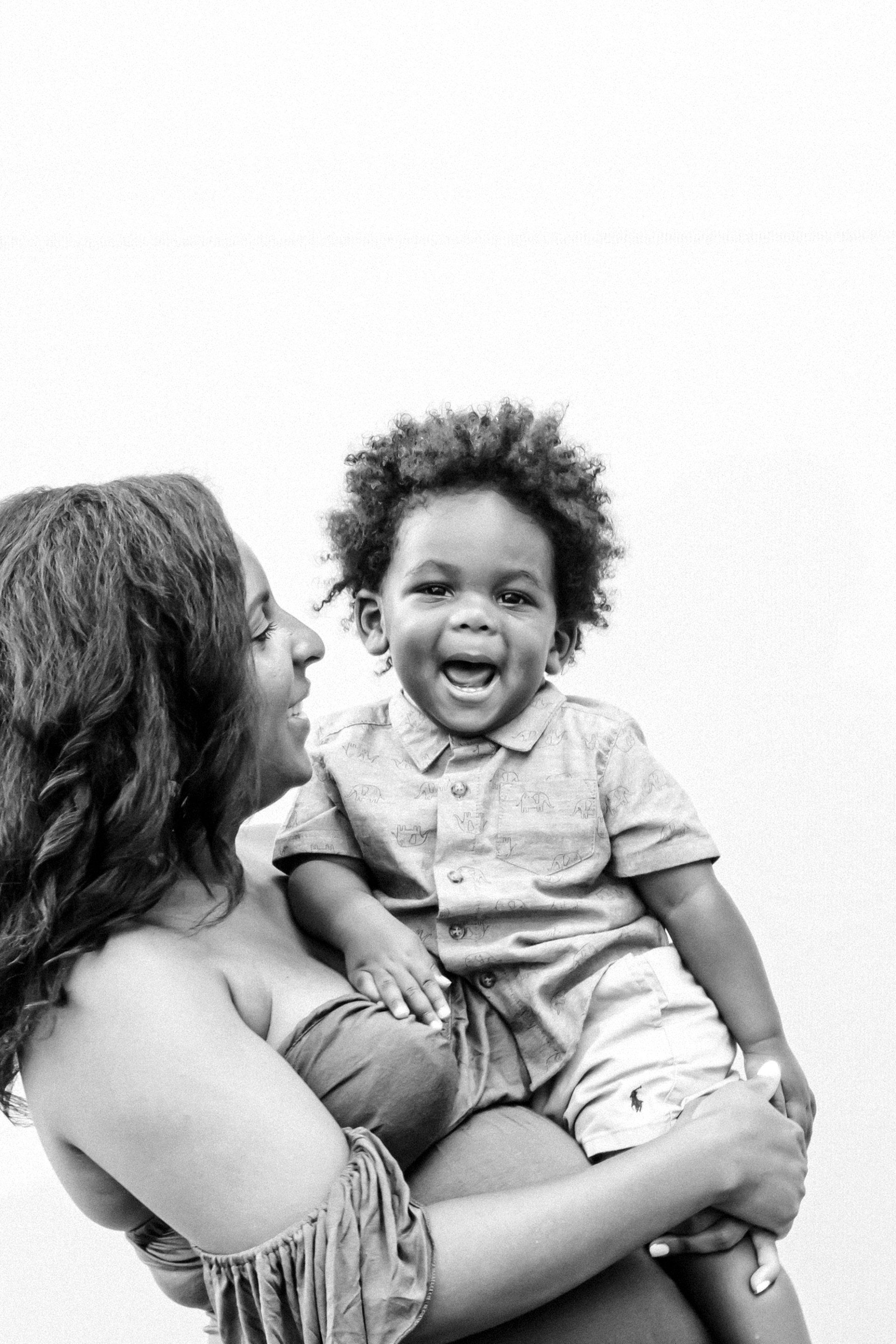 A woman is holding a baby in her arms and the baby is laughing.