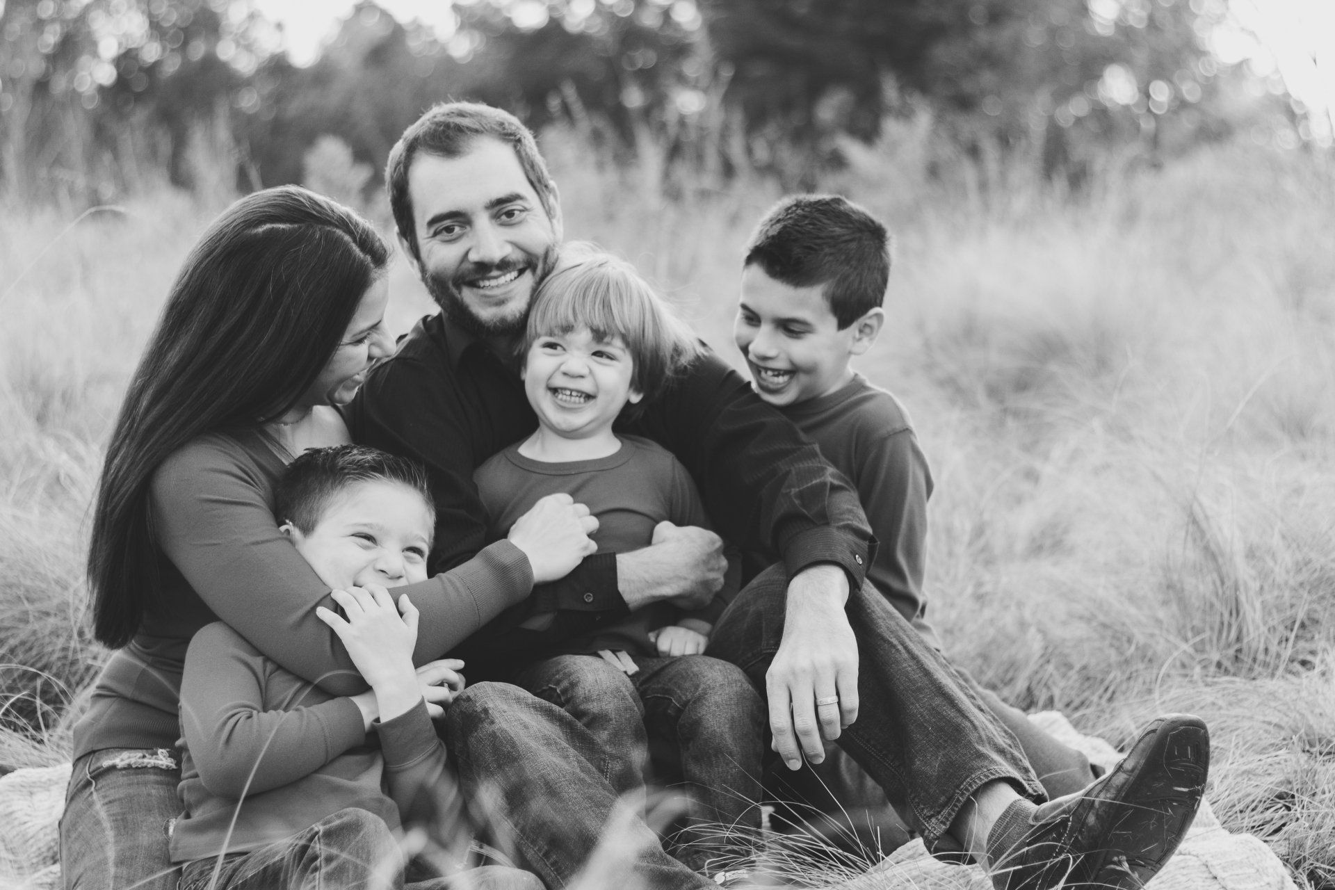 A black and white photo of a family sitting on a rock in a field.