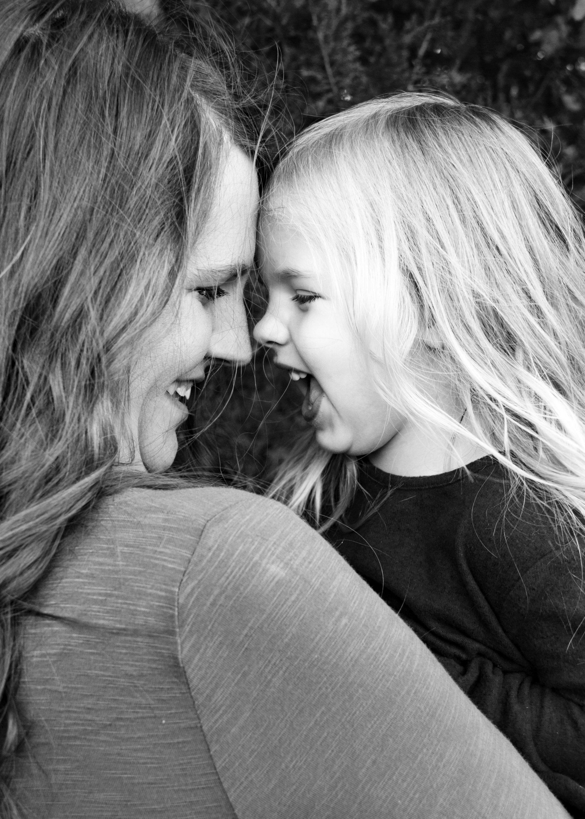 A woman and a little girl are looking at each other in a black and white photo.