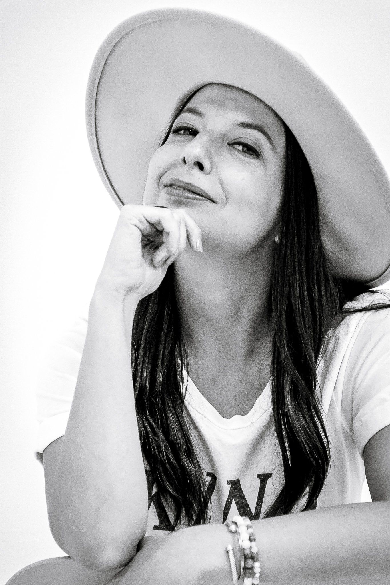 A black and white photo of a woman wearing a hat and a t-shirt.