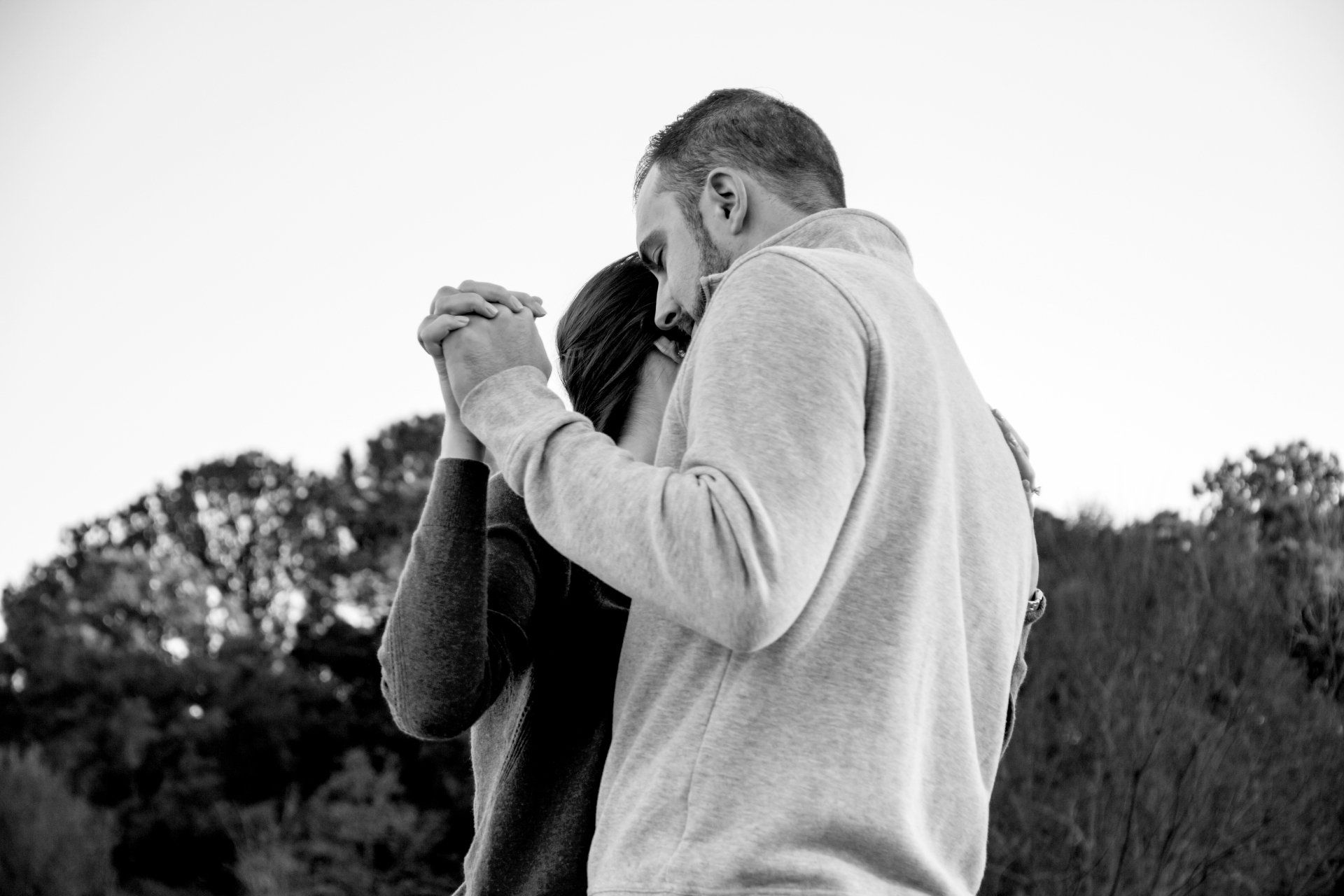 A man and a woman are hugging each other in a black and white photo.