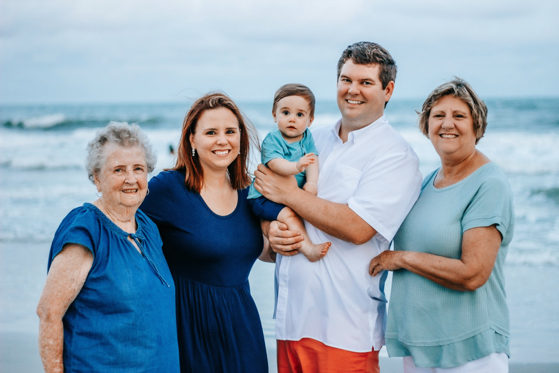 A family is posing for a picture on the beach.