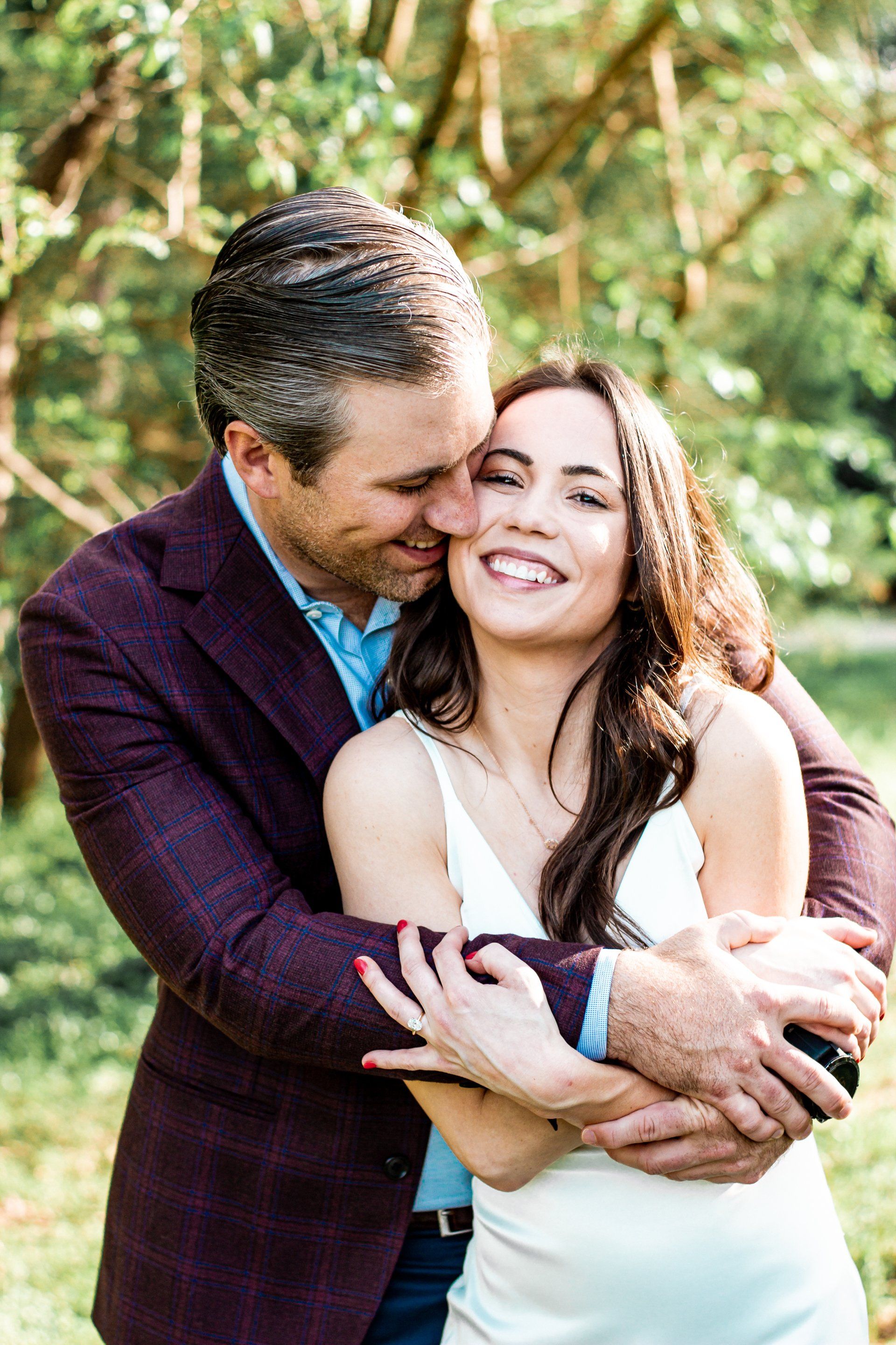 A man is kissing a woman on the cheek in a park.