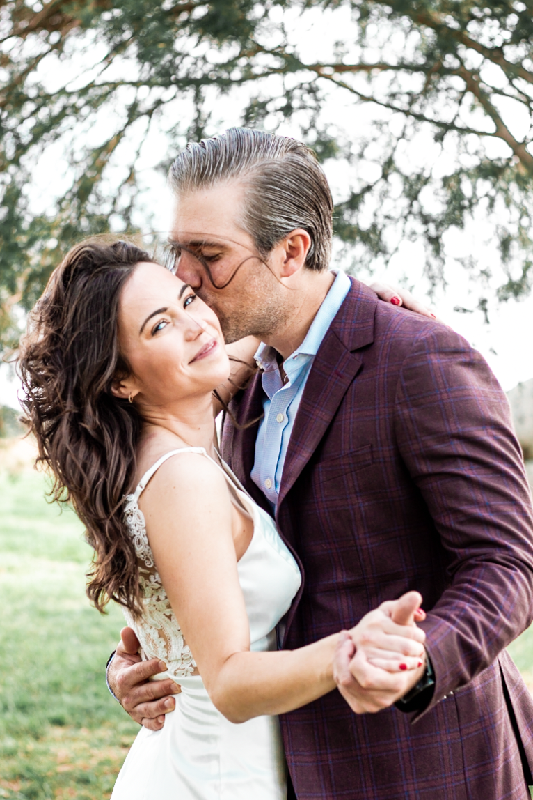A man is kissing a woman on the cheek while they are dancing.