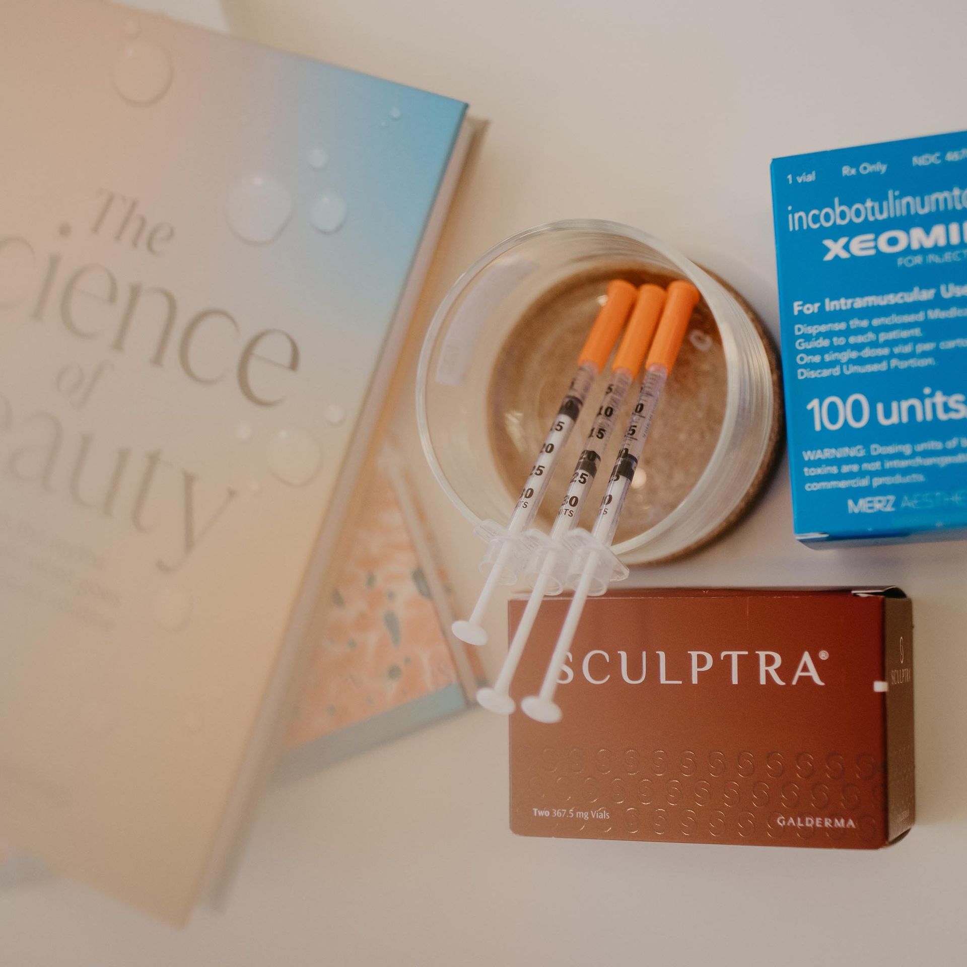 A box of sculptra syringes sits next to a book