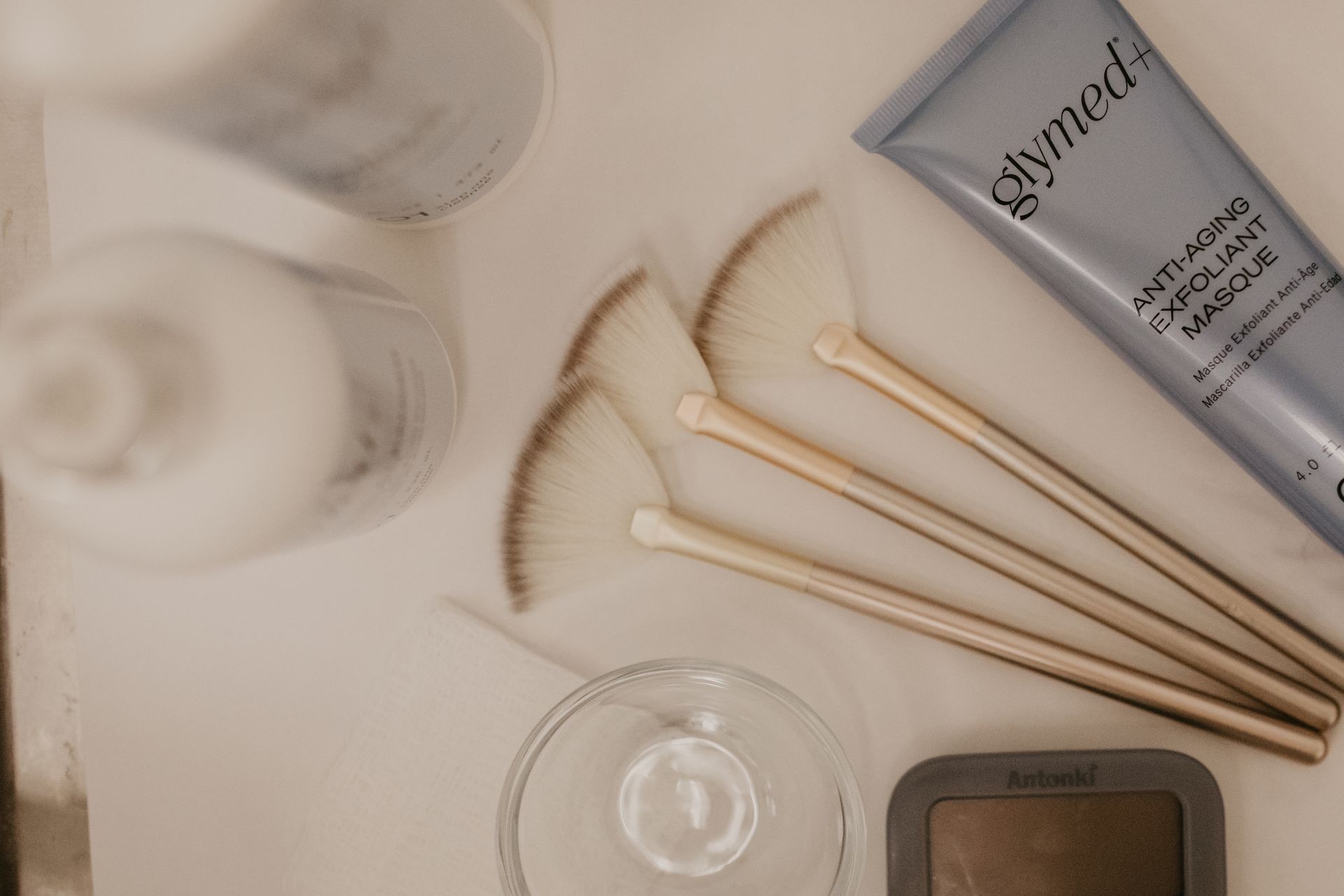 A bottle of glymed is on a table next to brushes