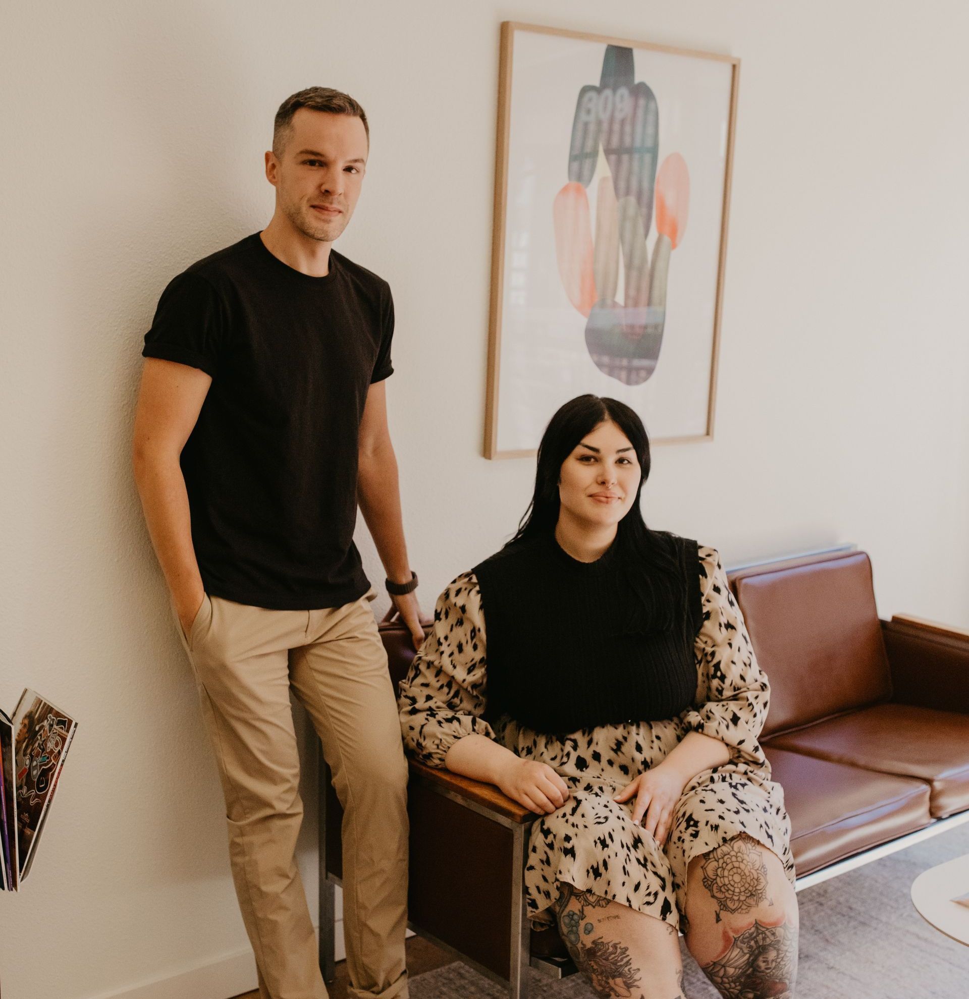 A man standing next to a woman sitting on a couch