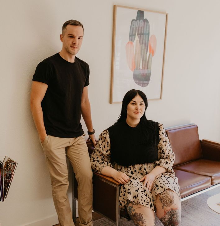 A man standing next to a woman sitting on a couch