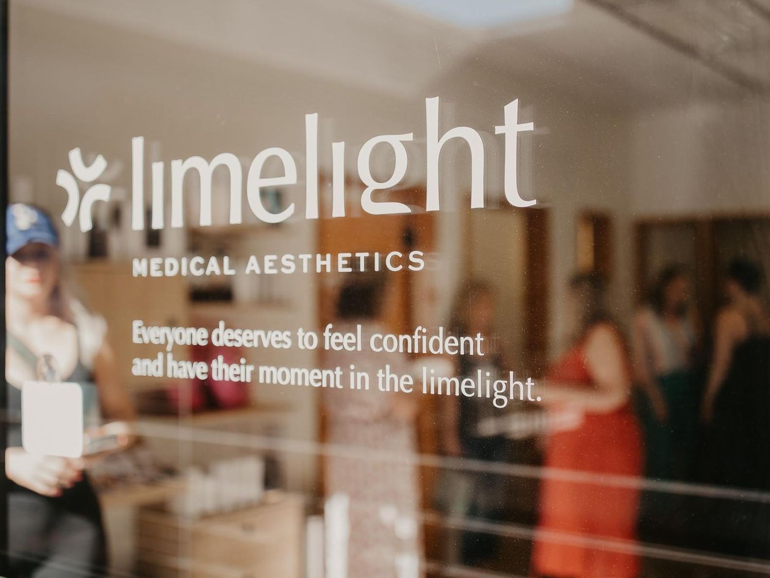 A group of people are standing in front of a limelight medical aesthetics store.