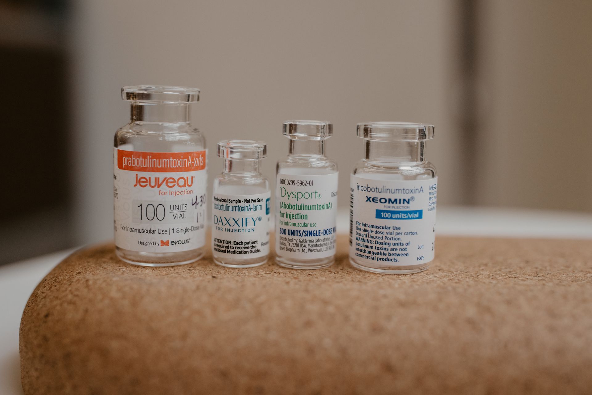 Four glass vials of medicine on a wooden surface.