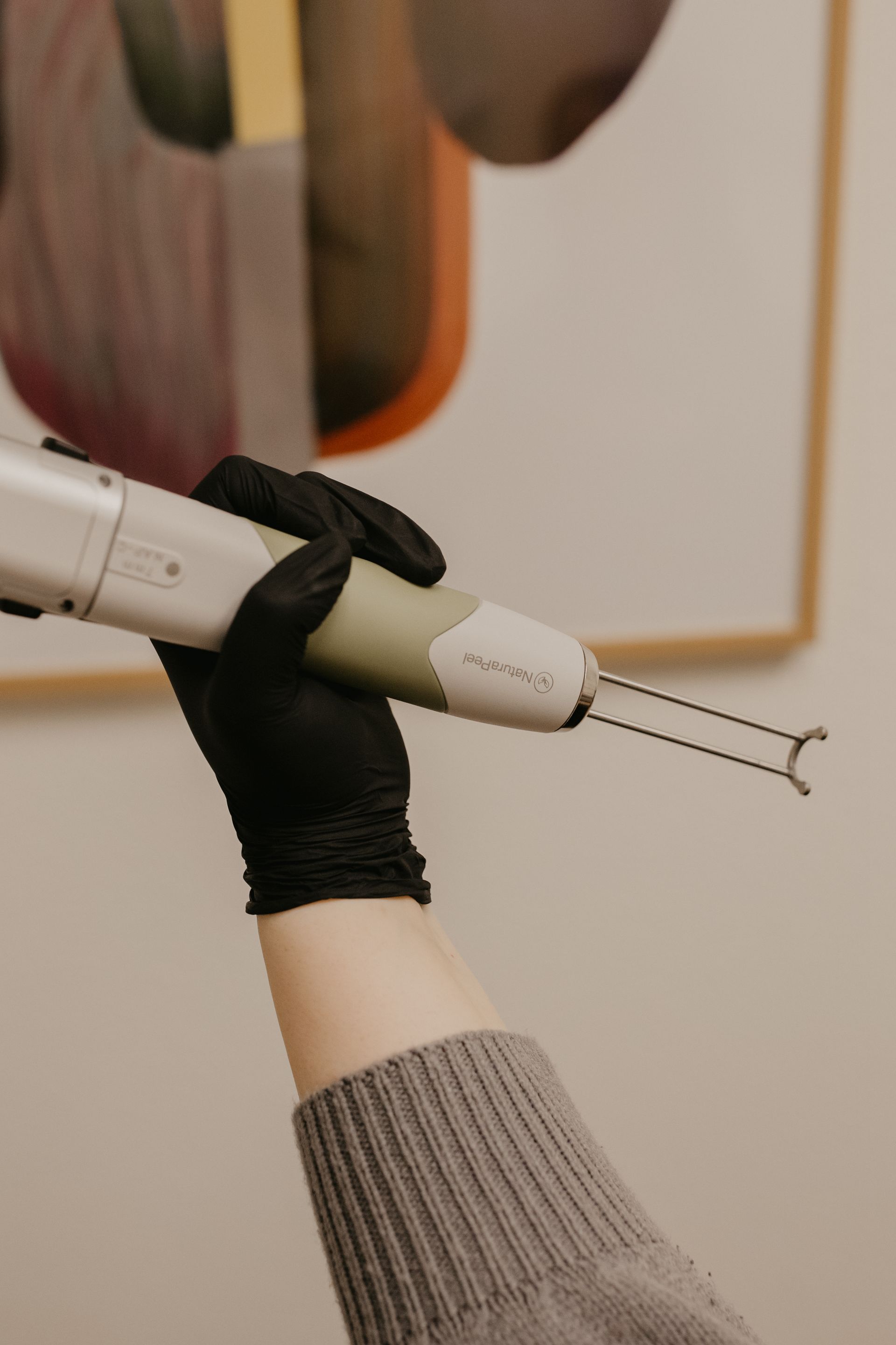 A person wearing a black glove holds a medical device with two prongs.