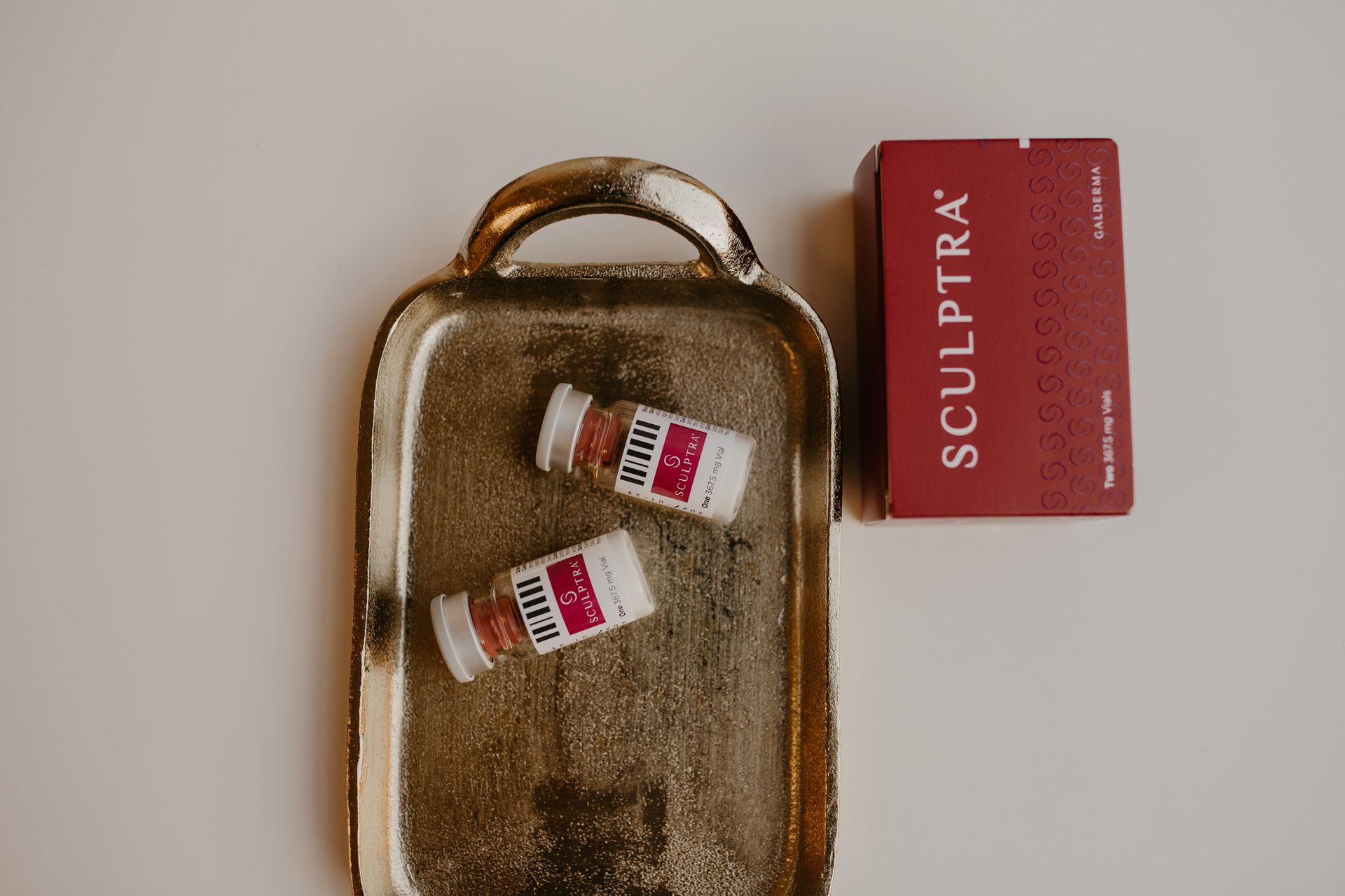 A box of sculptra syringes sits next to a book