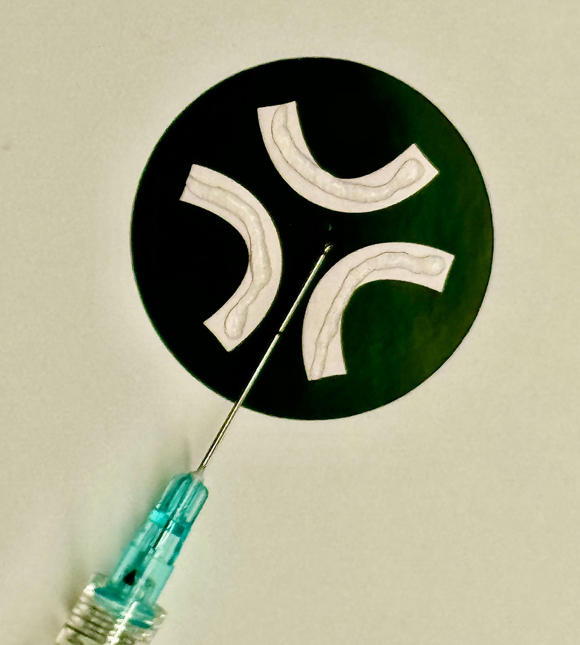 A syringe with a needle sticking out of it is next to a circle with a smiley face on it