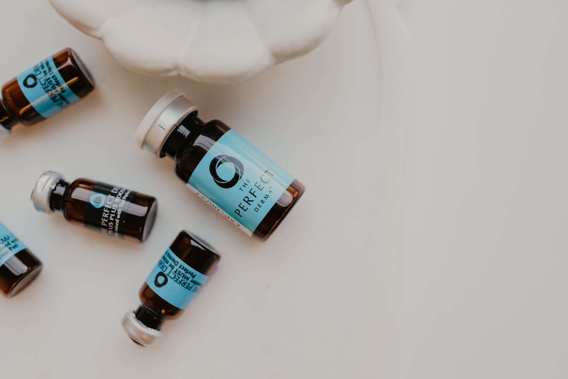 Small brown vials with blue labels scattered on a white surface, possibly product shots.