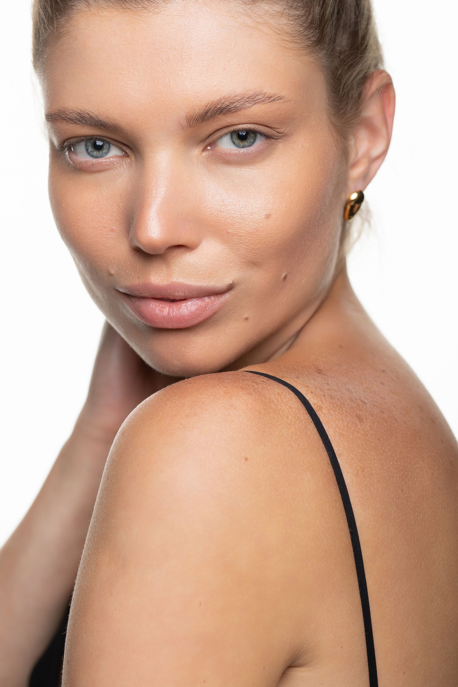 A woman without makeup is looking over her shoulder at the camera.