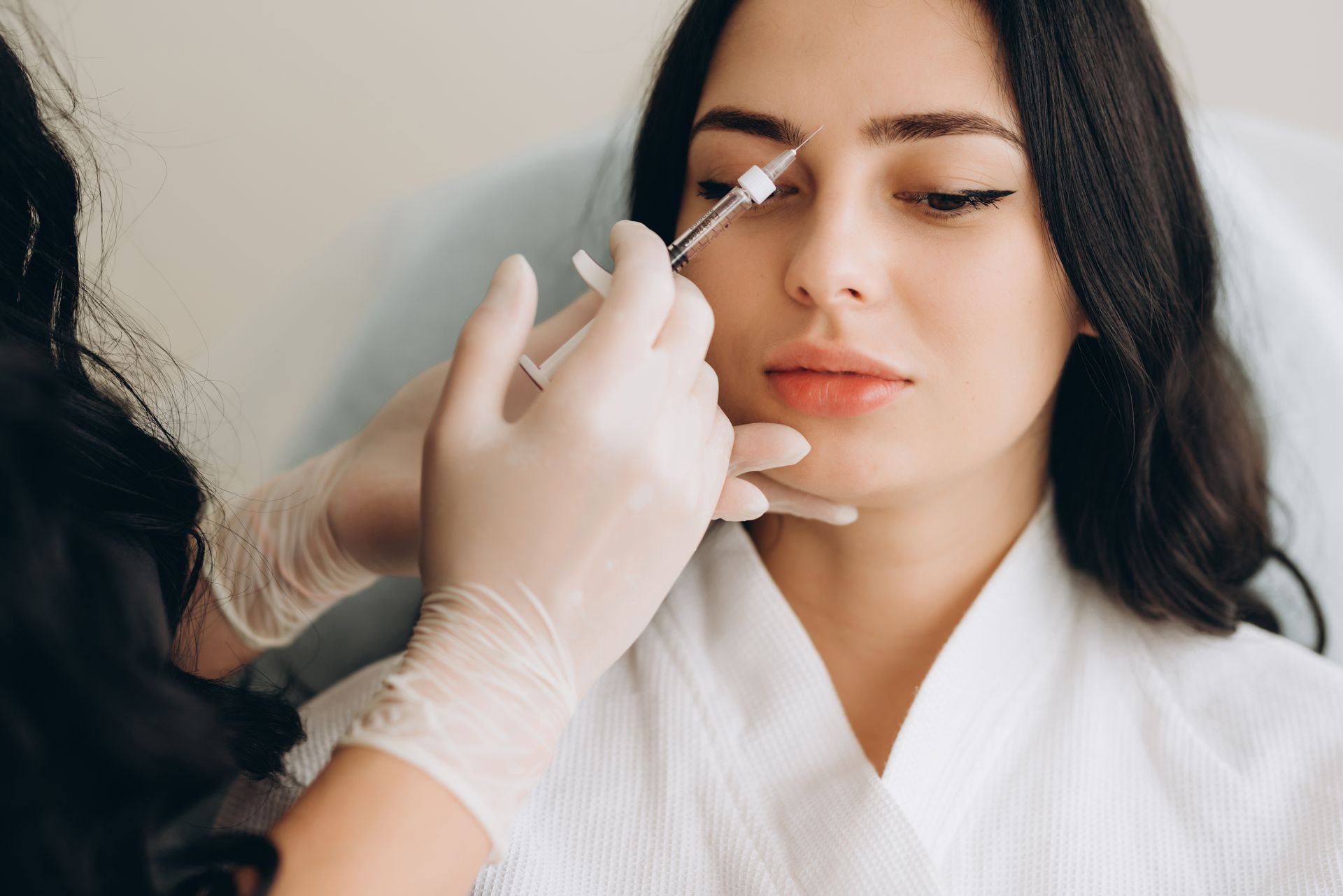 A woman is getting a botox injection in her face.