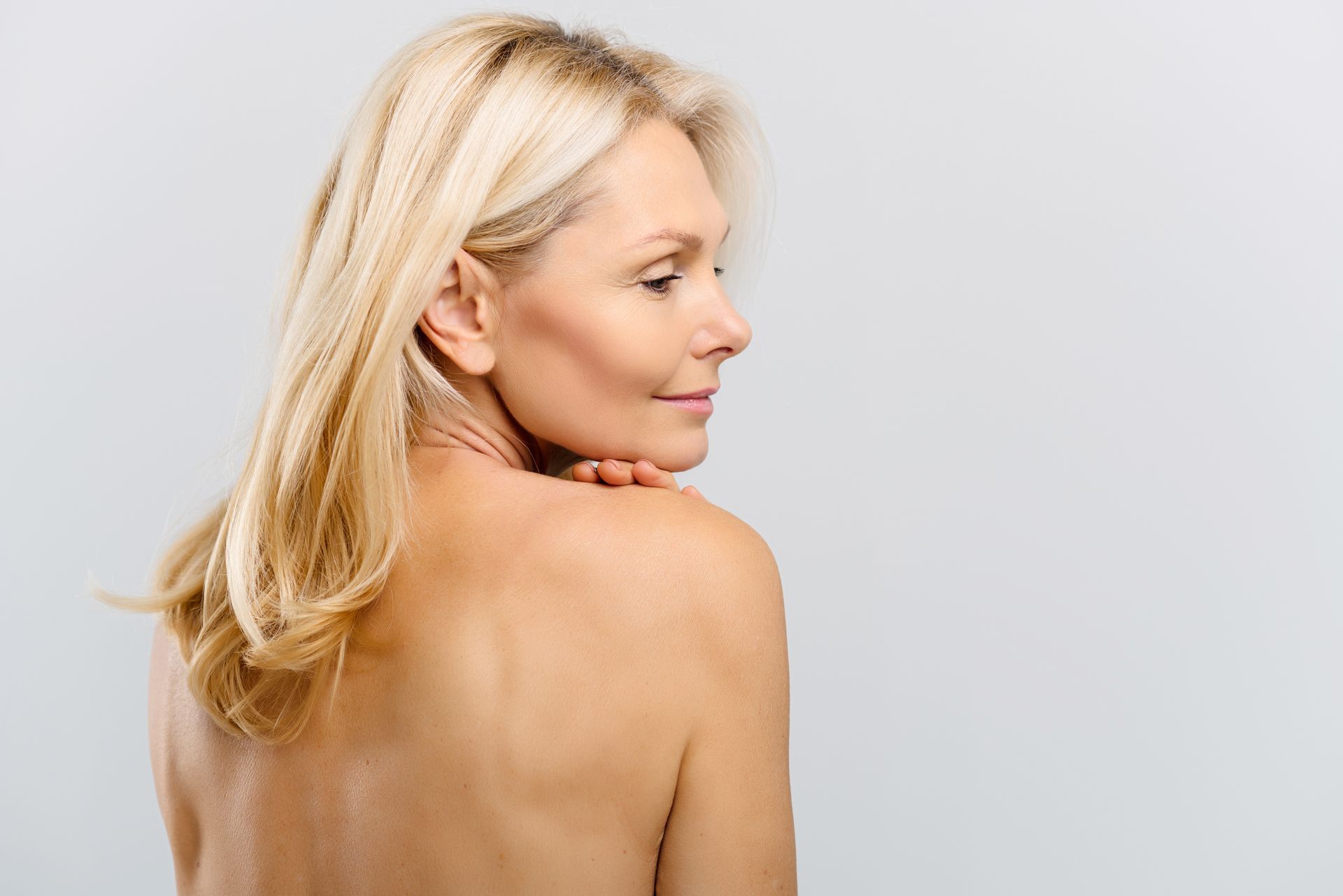 A woman without a shirt is looking over her shoulder.