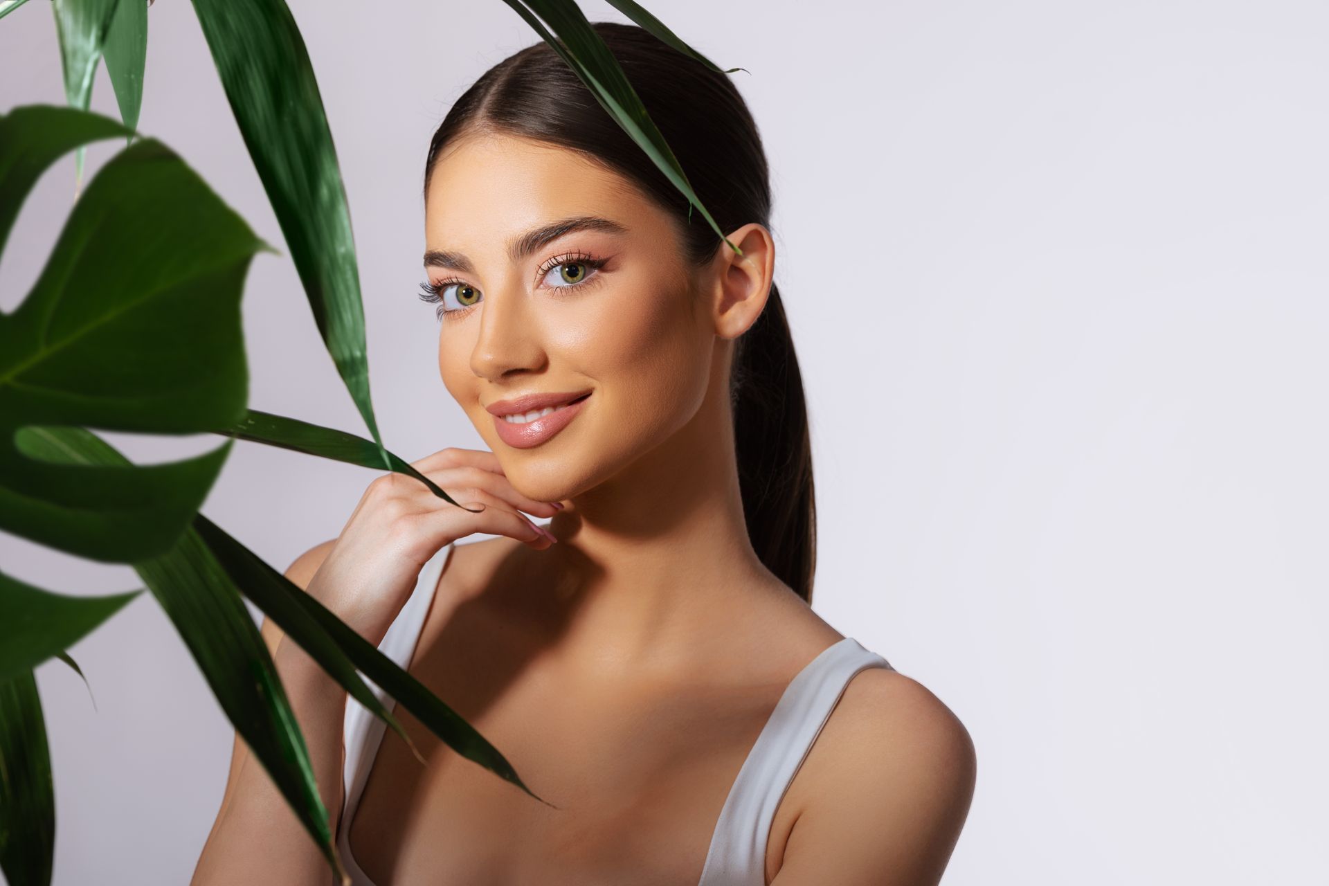 A woman is standing in front of a plant with green leaves.