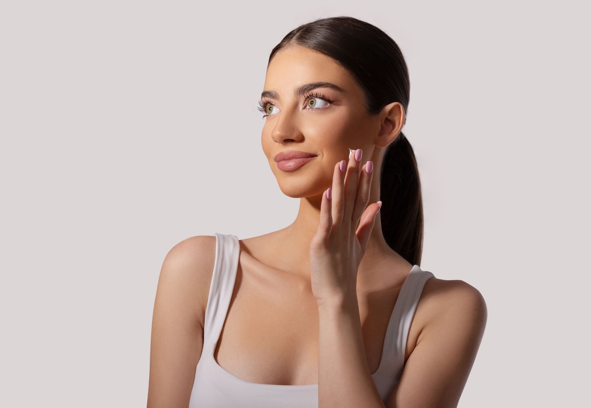 A woman is touching her face with her hand and smiling.