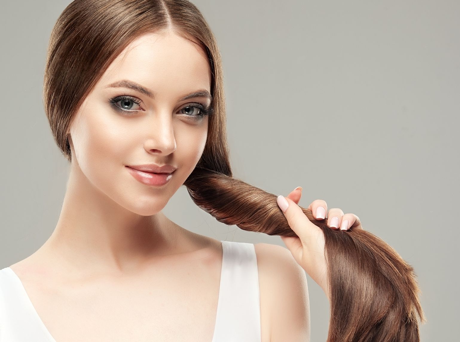 A woman is holding her hair in a ponytail.