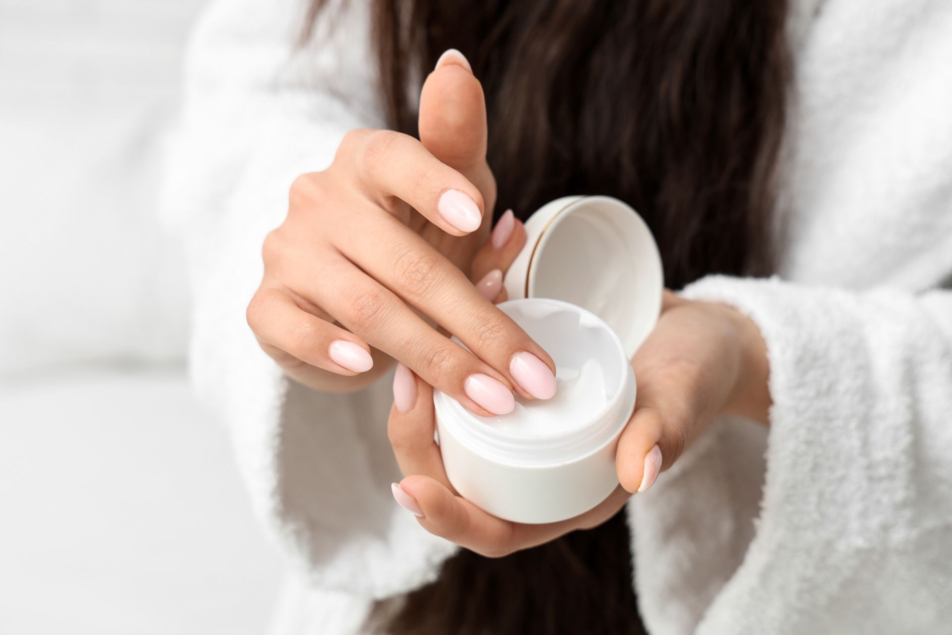 A woman is holding a jar of cream in her hands.