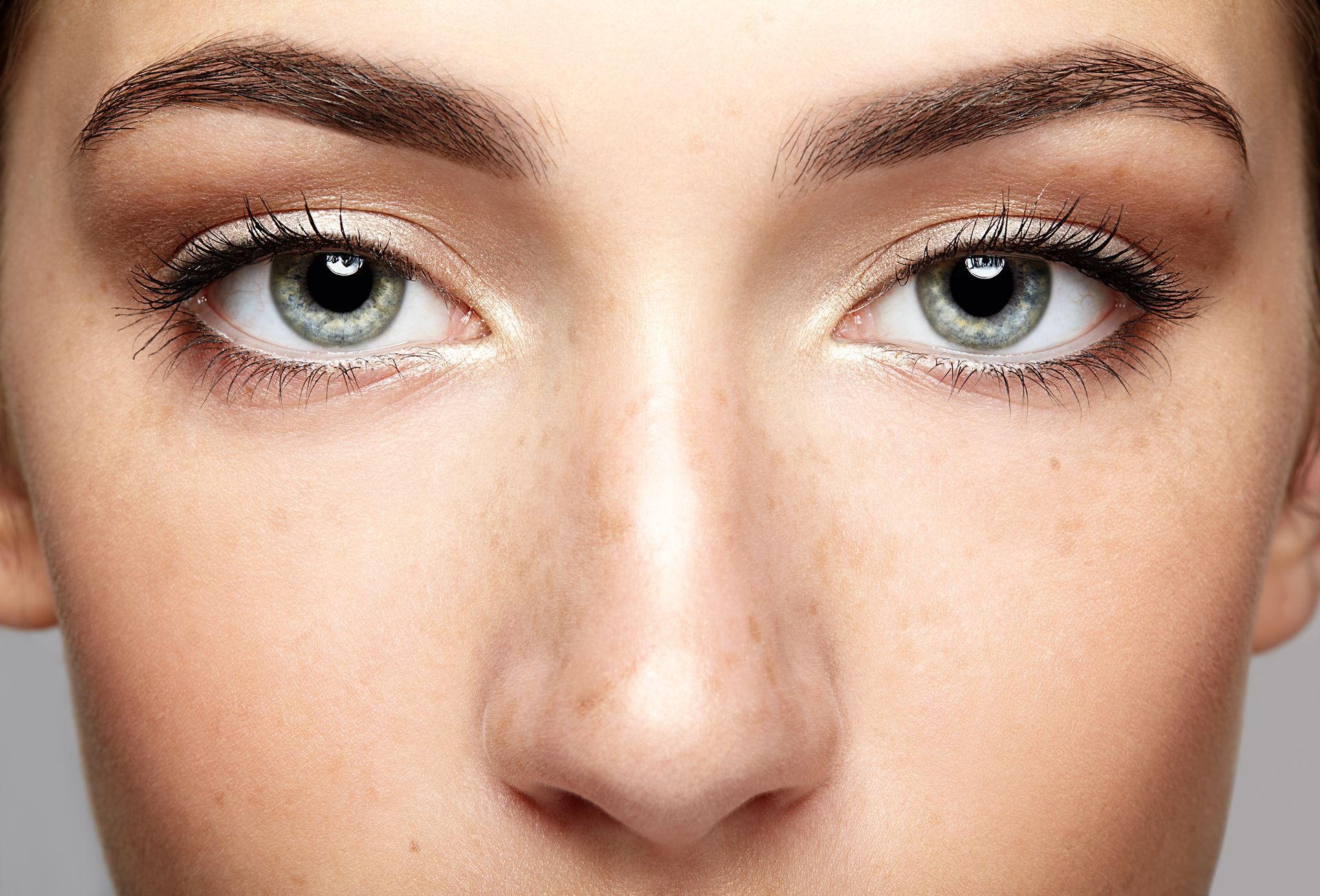 A close up of a woman 's face with green eyes and brown eyebrows.