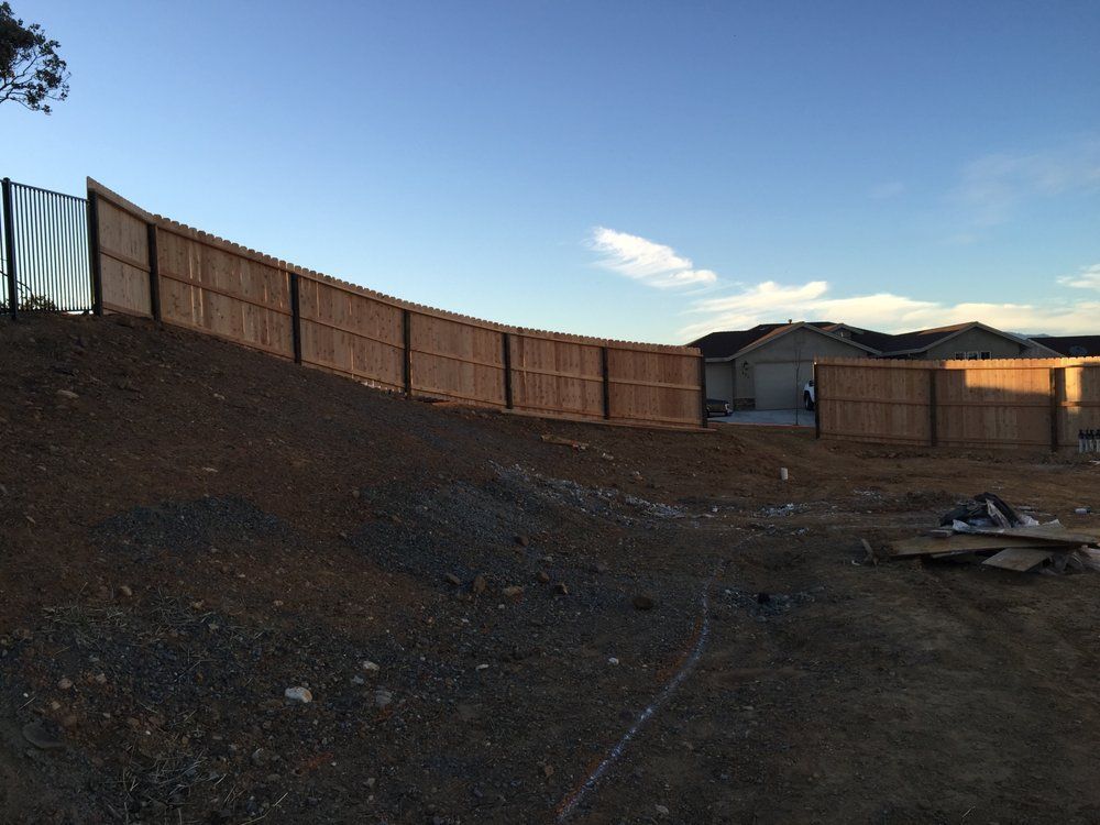 Empty dirt lot beside a wooden fence under a blue evening sky